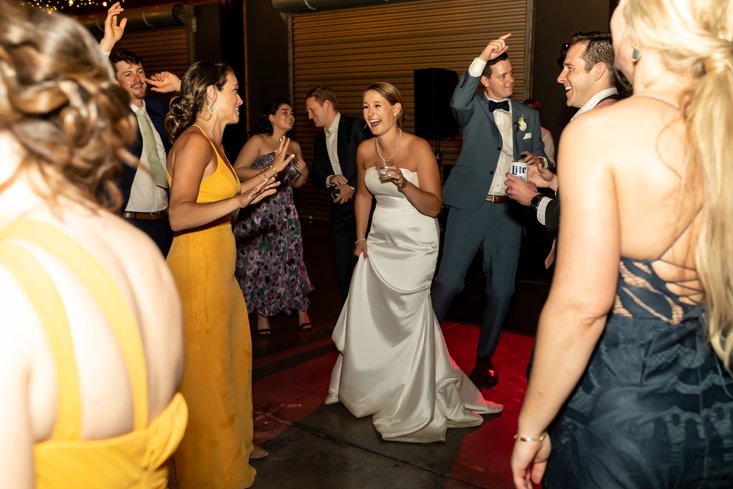 Wedding guests dance together energetically on a crowded dance floor at an evening reception.