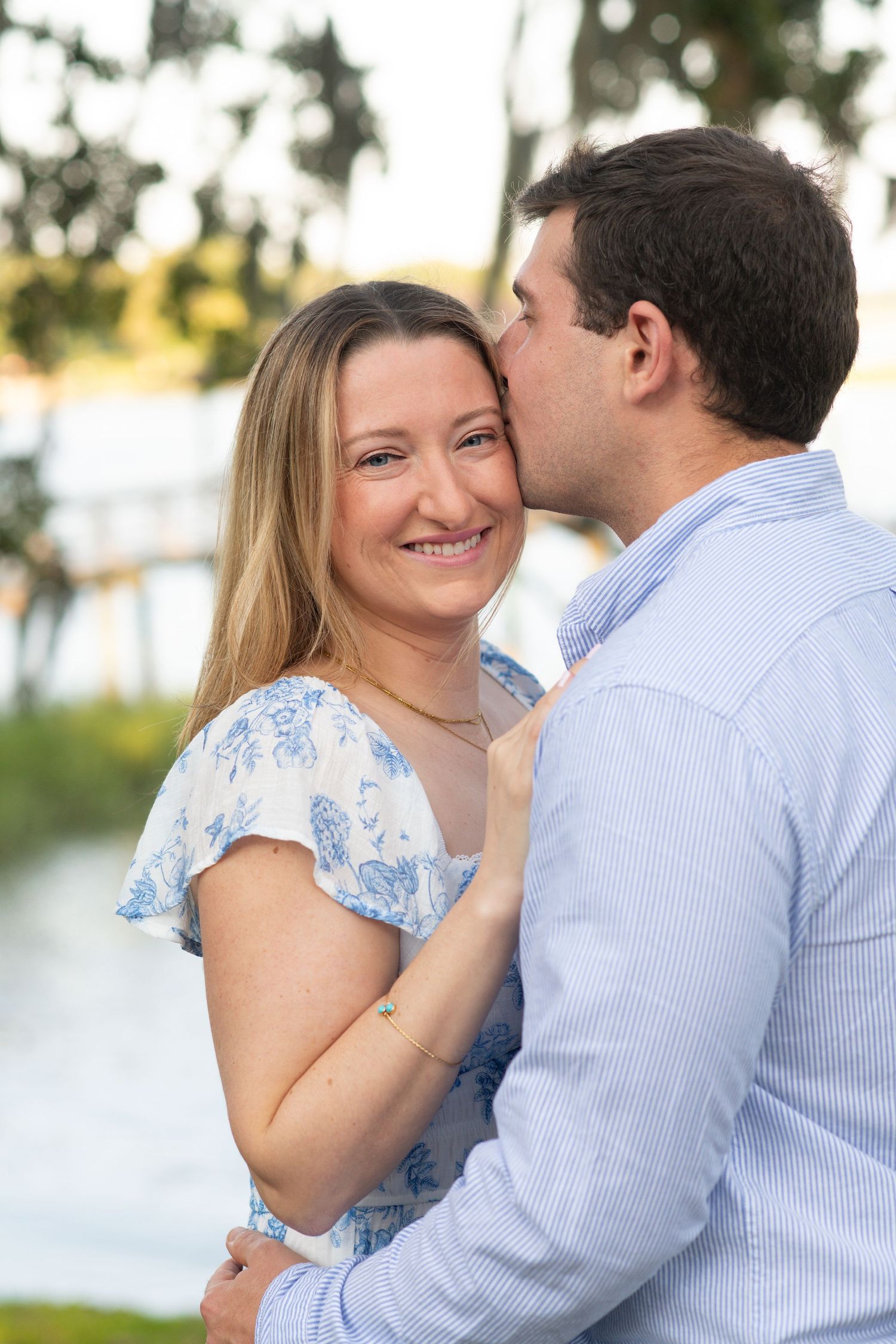 A romantic couple in blue and white outfits share tender moments in an outdoor setting with palm trees.