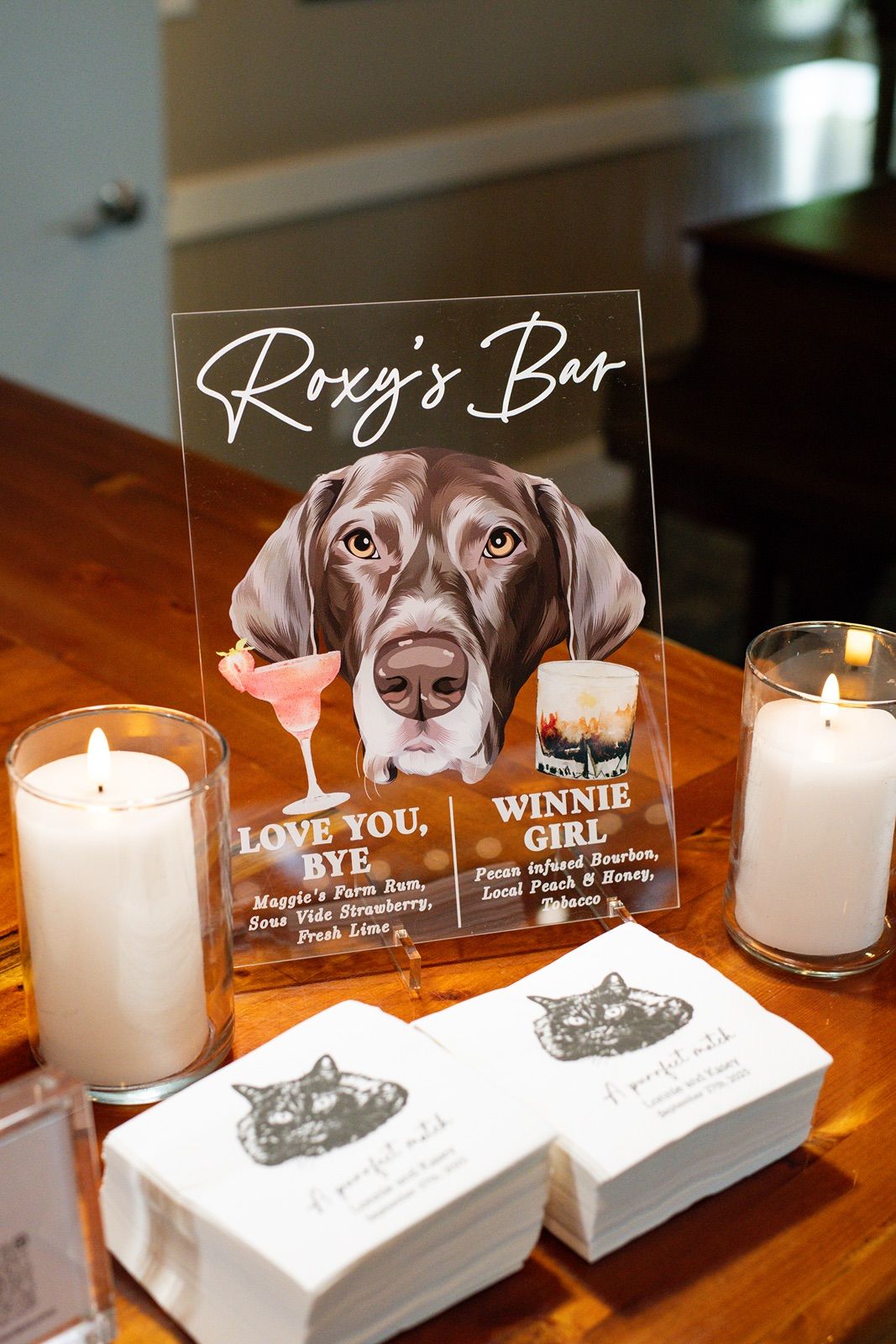 Custom acrylic bar signs featuring cute dog illustrations and drink menu items with candles.