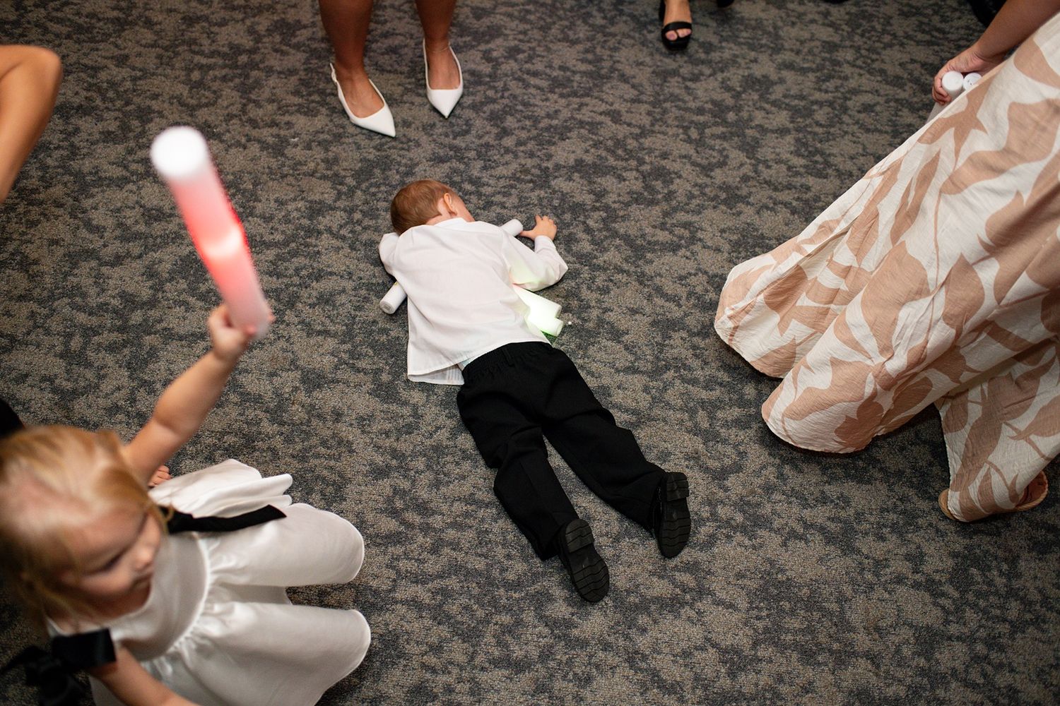 Dancing feet in formal shoes and dresses move across a textured stone floor at an elegant event.