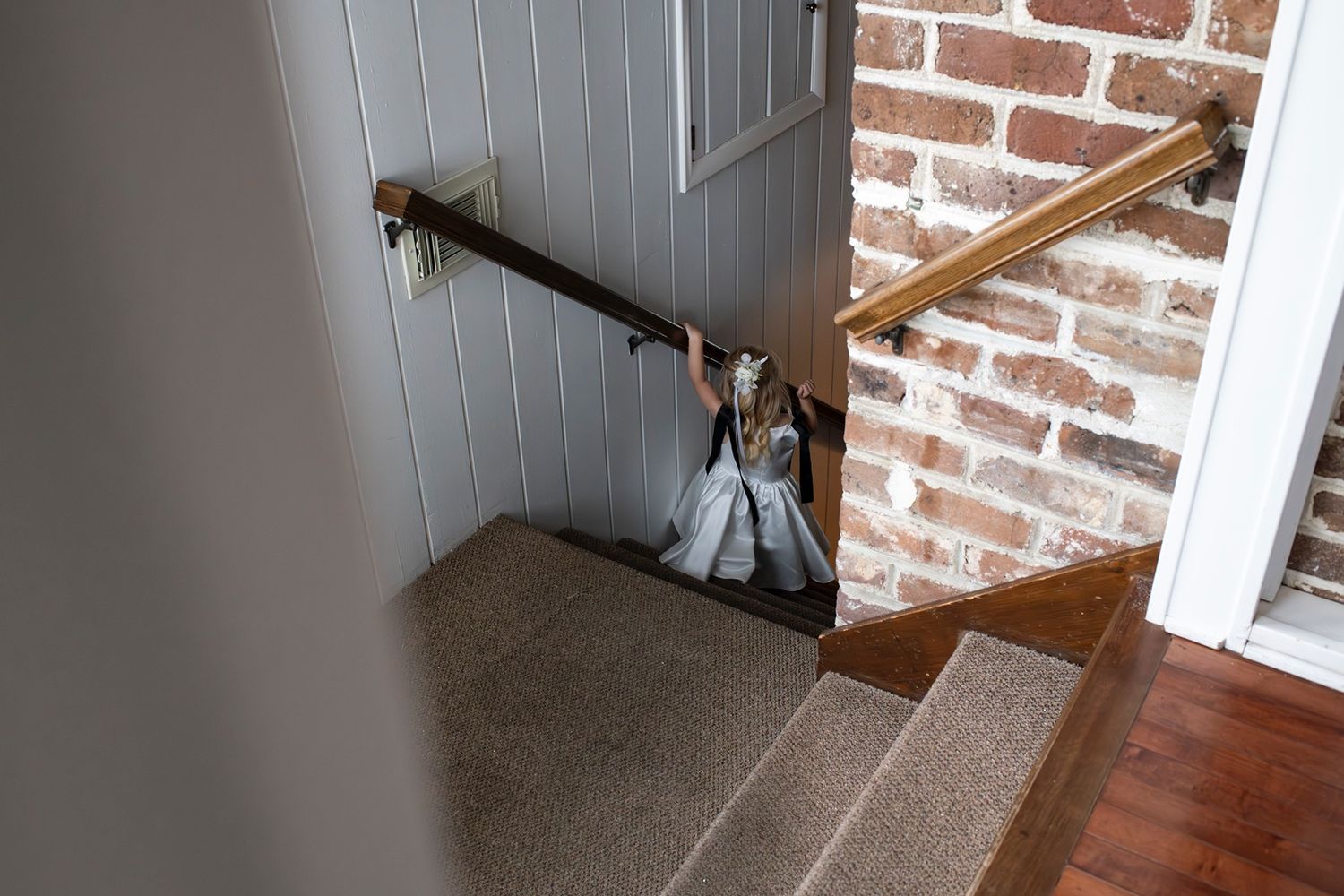 A wooden staircase with brick wall and white paneling in a modern interior setting.