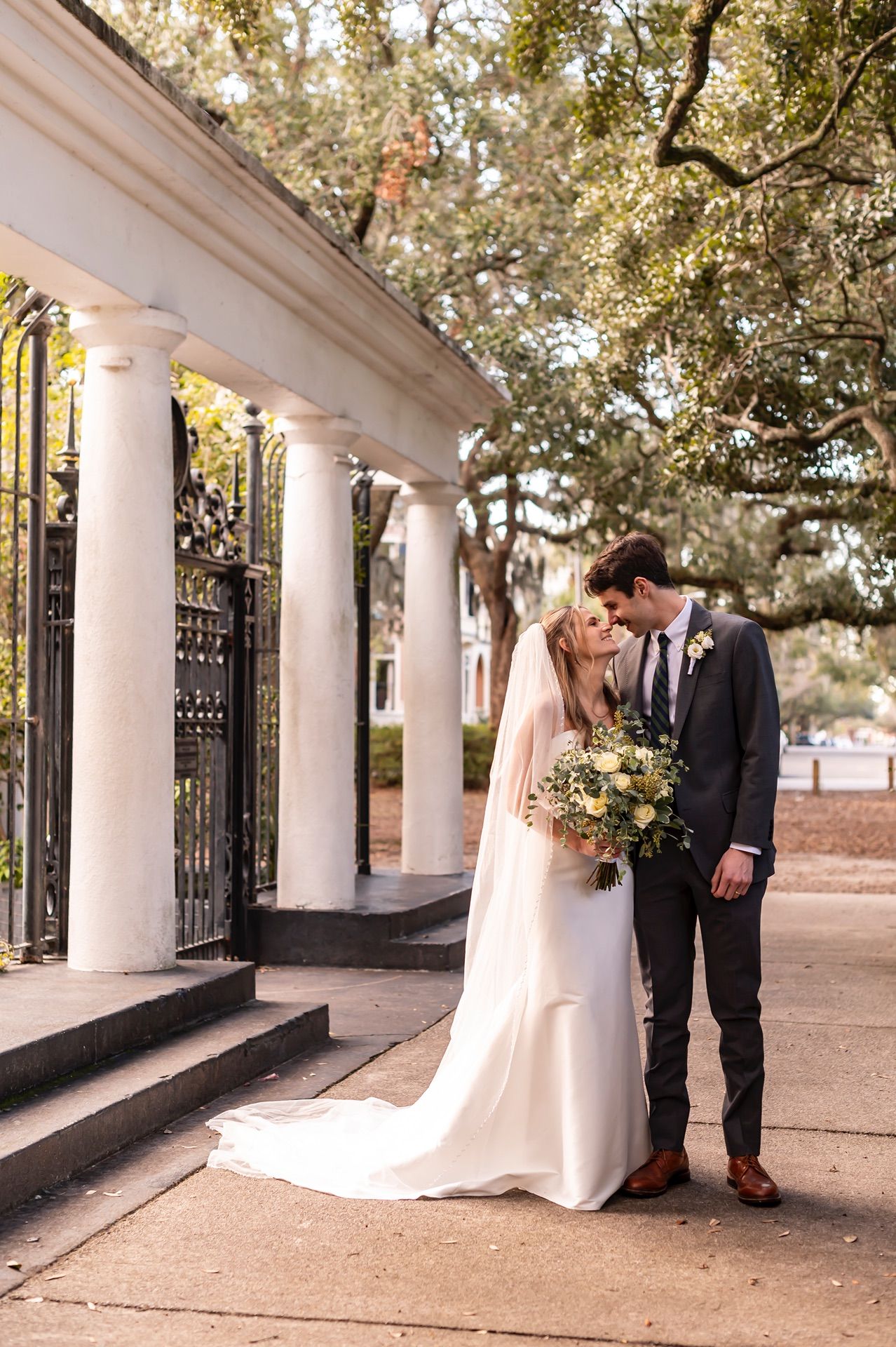 A romantic wedding photoshoot series under a white columned porch with trees and natural light creating an elegant atmosphere.