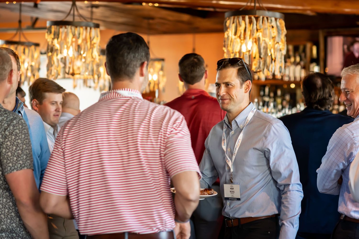Business networking event with professionals mingling under crystal chandeliers in Savannah, Georgia.