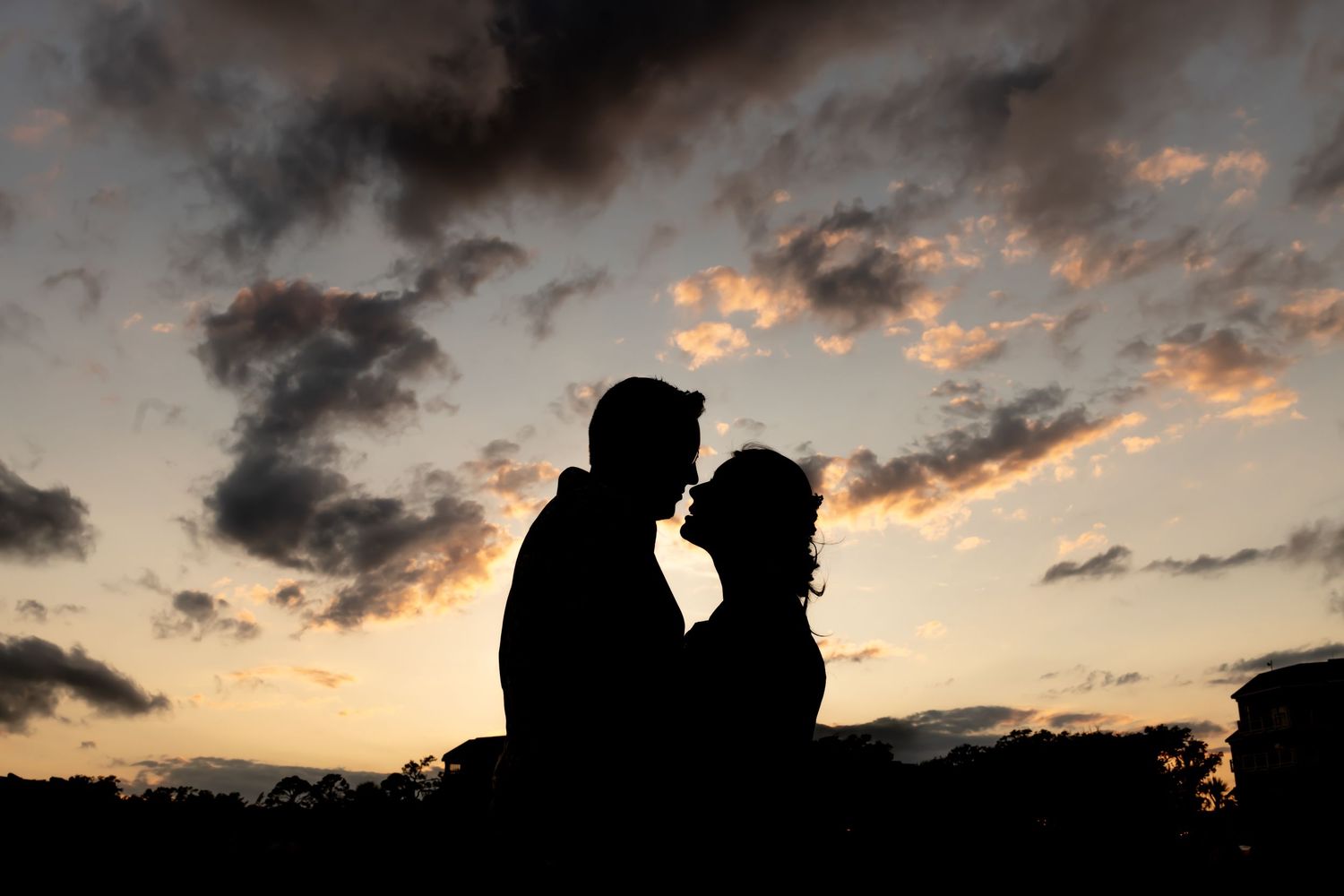 Silhouette of couple against dramatic sunset sky with pink and orange clouds.