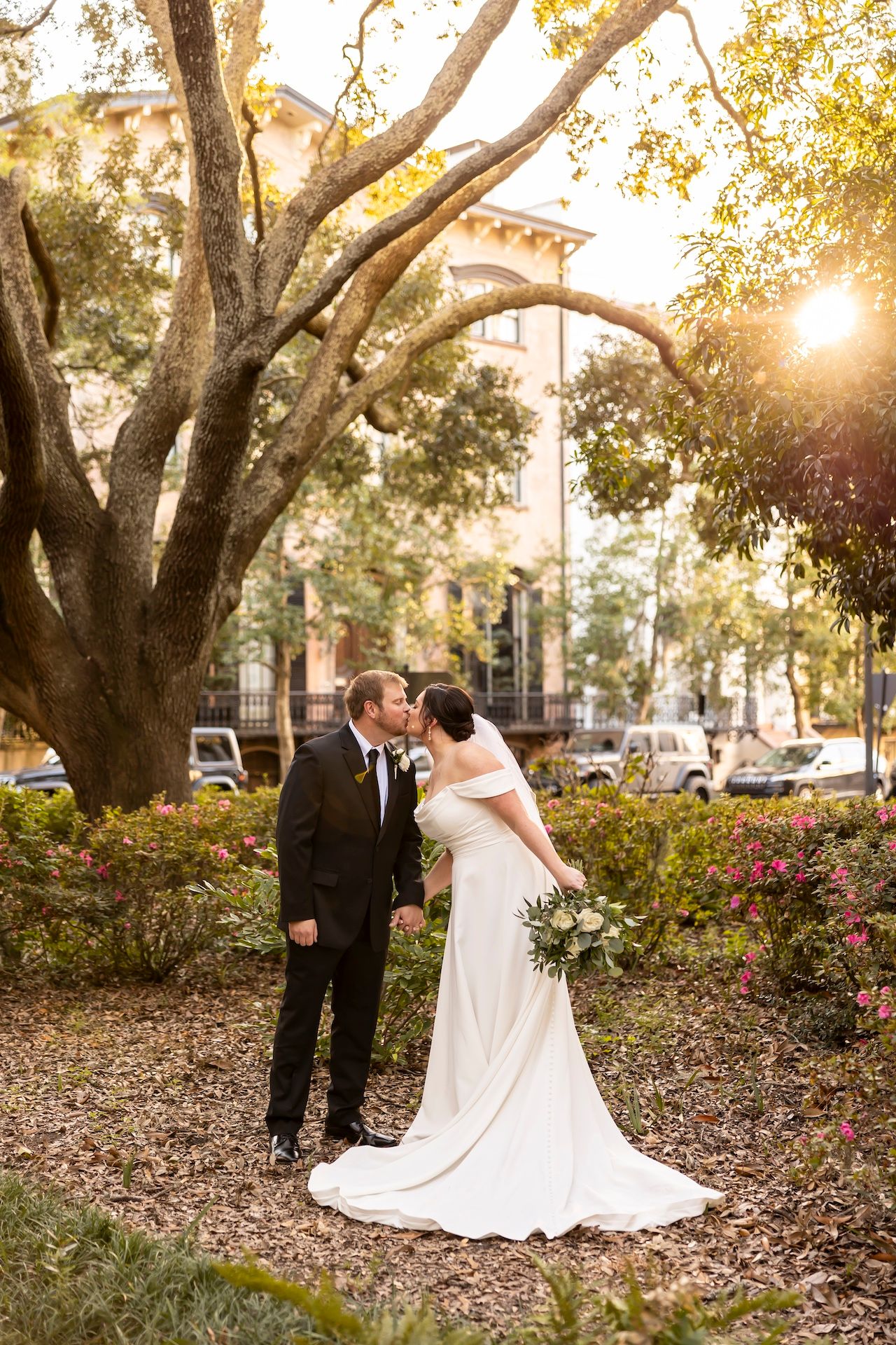 A romantic moment under a large oak tree at sunset in a garden setting with warm golden light filtering through.