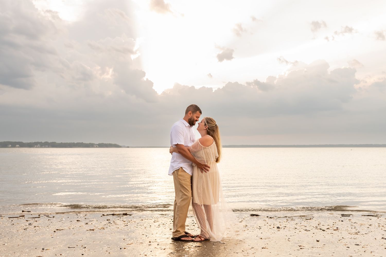 A romantic couple embraces on a peaceful beach at sunset as gentle waves roll onto the shore.