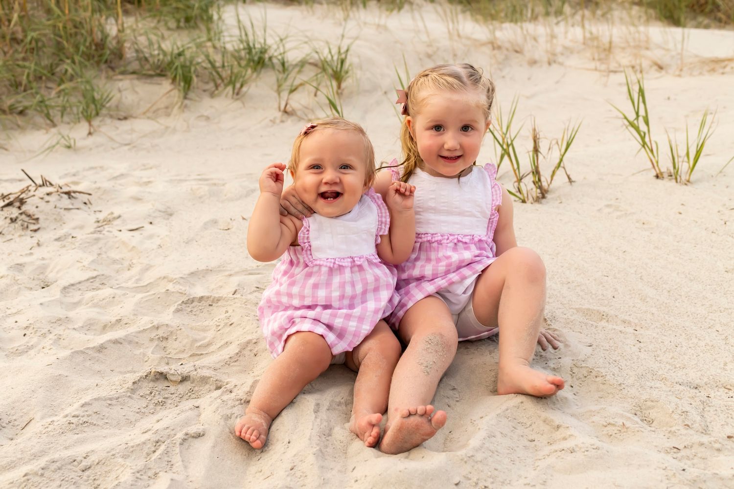 A series of candid beach photos showing children playing and laughing together in the sand while wearing pink outfits.