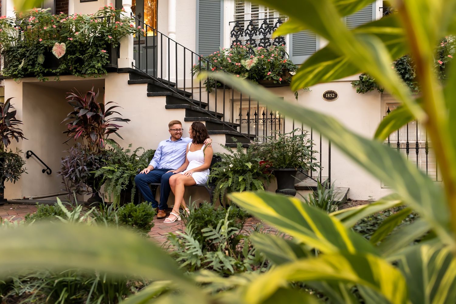 A lush tropical garden surrounds an outdoor staircase leading to a modern residential building.