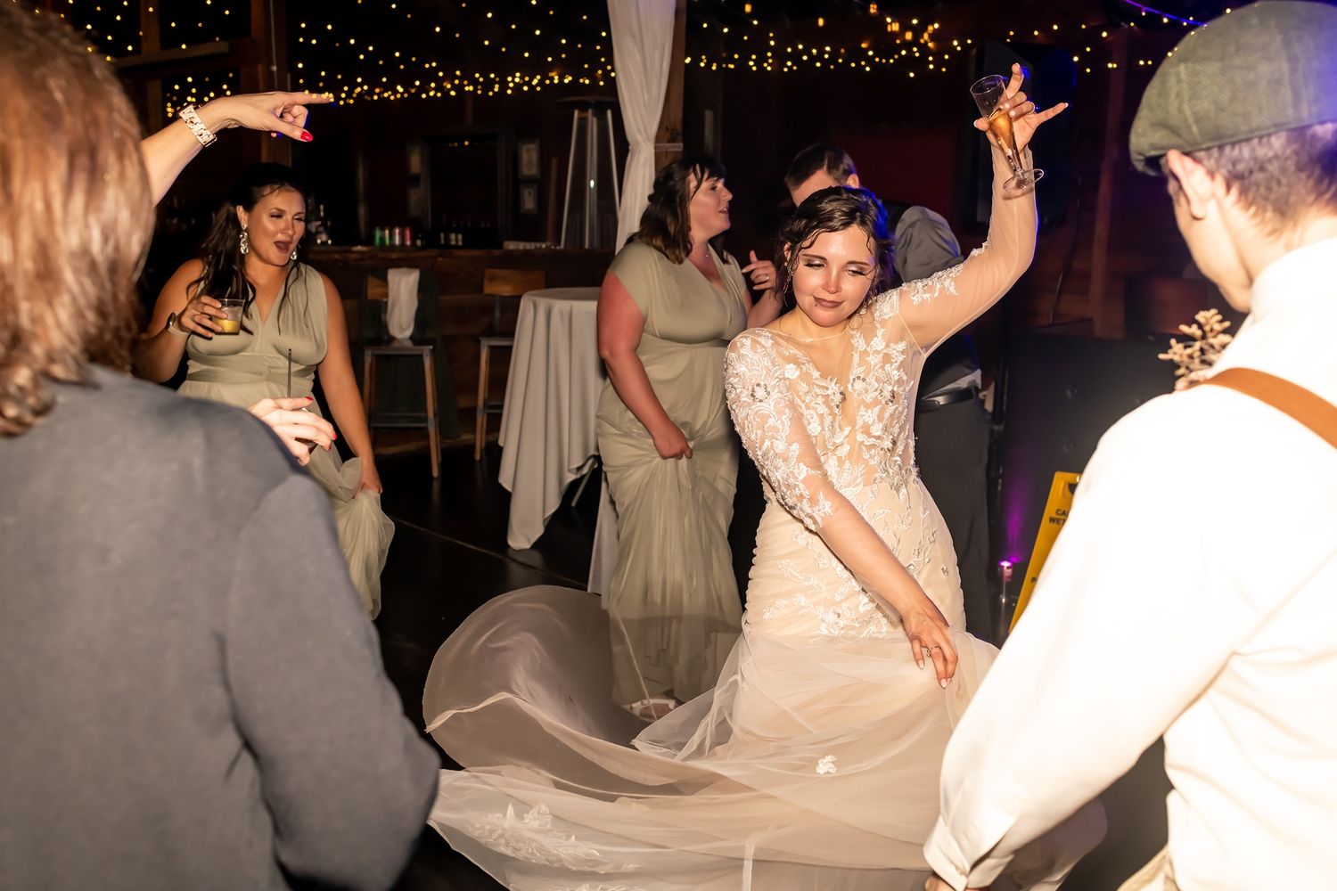 Wedding guests dance and enjoy themselves on the dance floor at an indoor evening reception celebration.