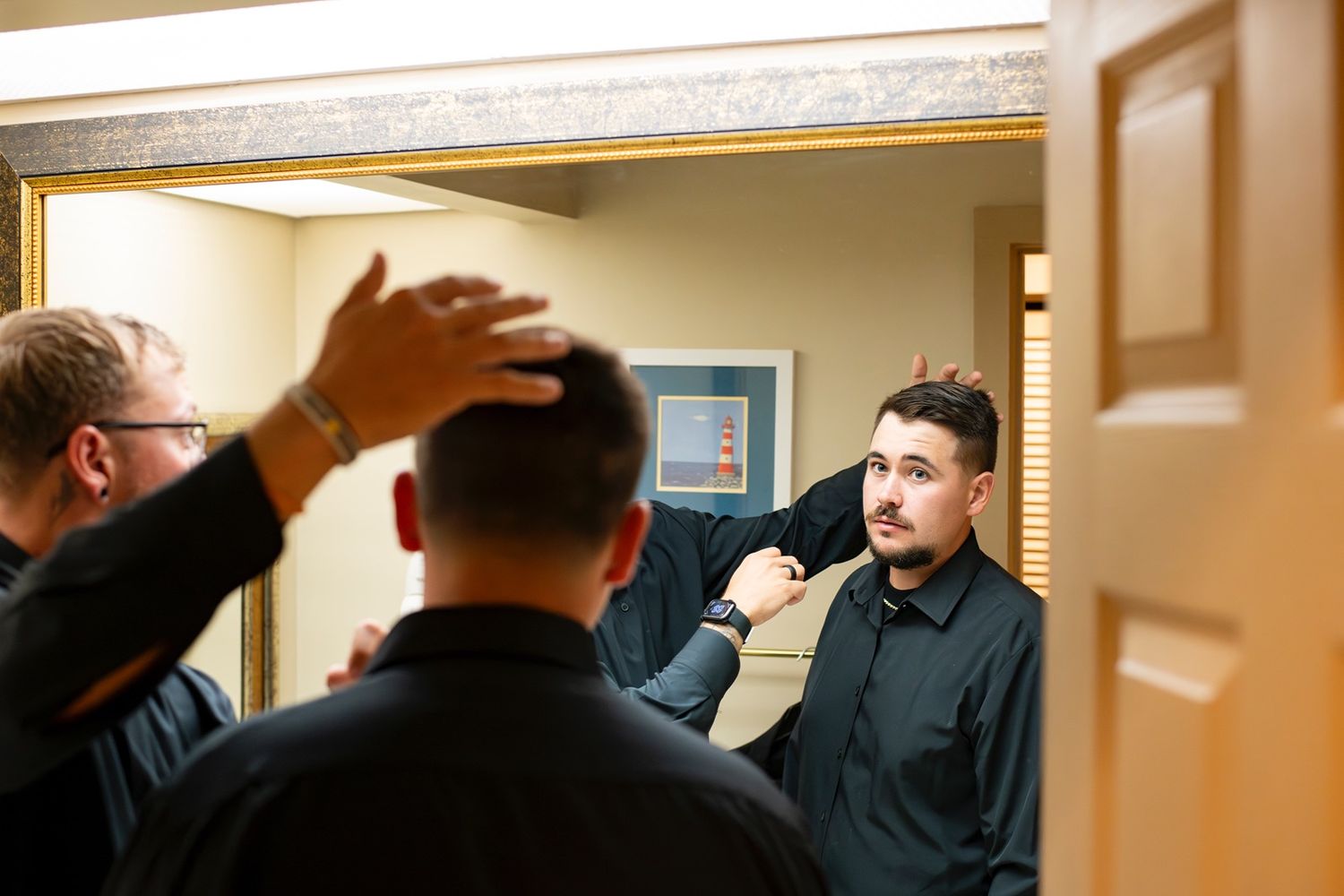 Two people engage in an energetic conversation while standing in a hallway near a mirror.