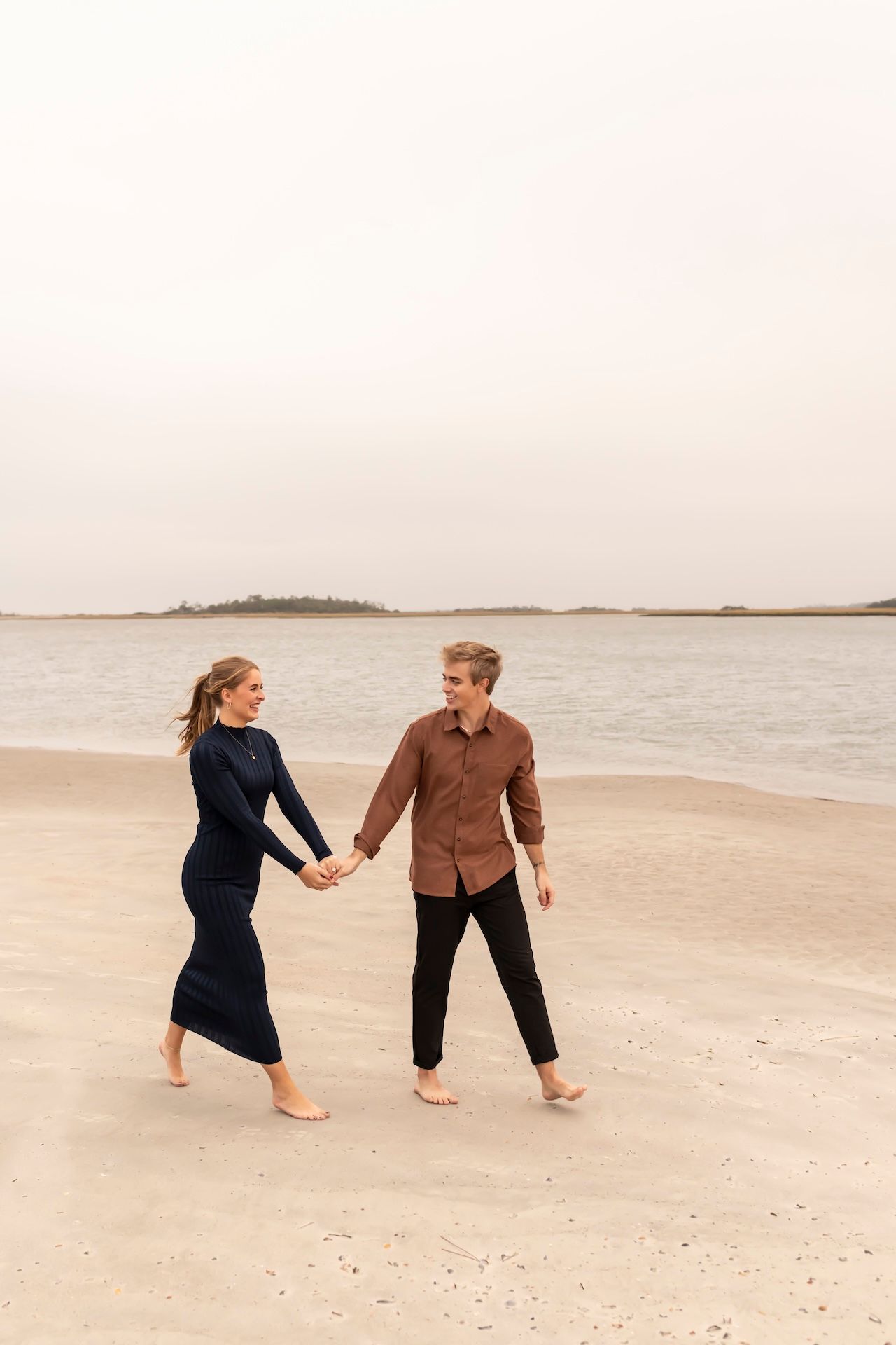 Couple walking on Tybee Island beach during a cloudy day.