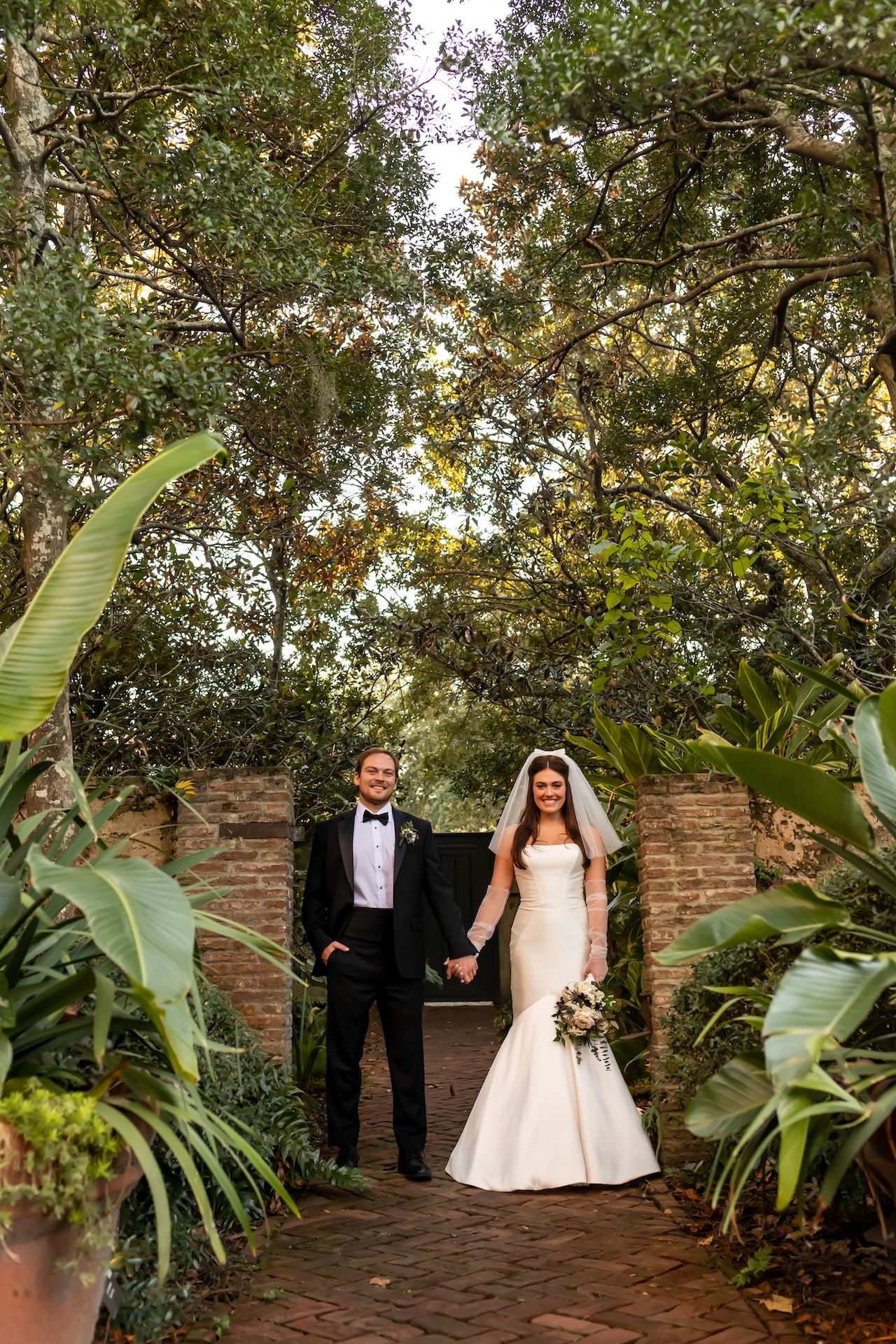 A bride and groom poses in the garden at their Ships of the Sea wedding.