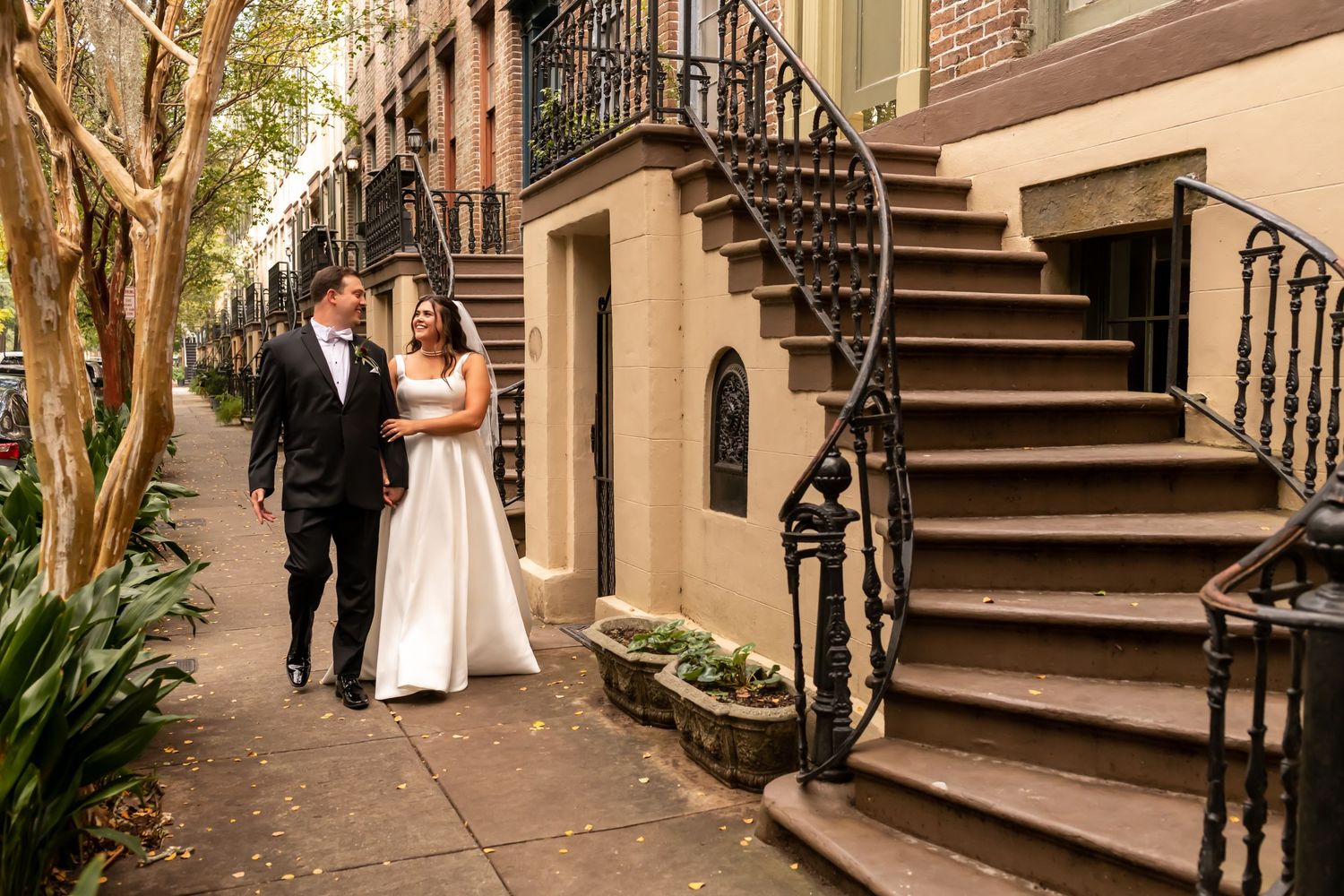 Historic brownstone staircase with ornate railings and brick walls creates elegant wedding venue setting.