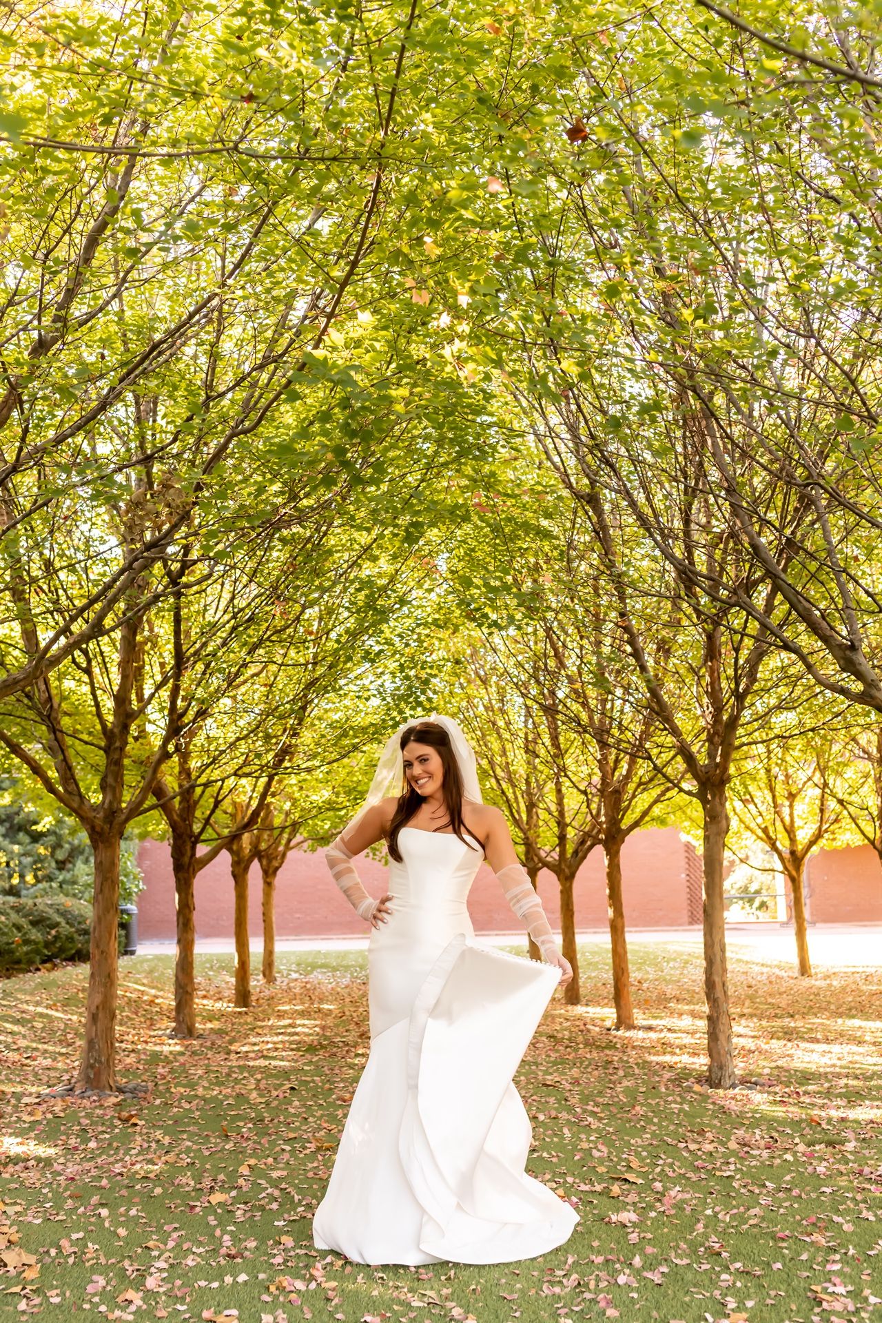 Elegant white dress flowing in the breeze among a scenic grove of autumn trees during golden hour sunset.