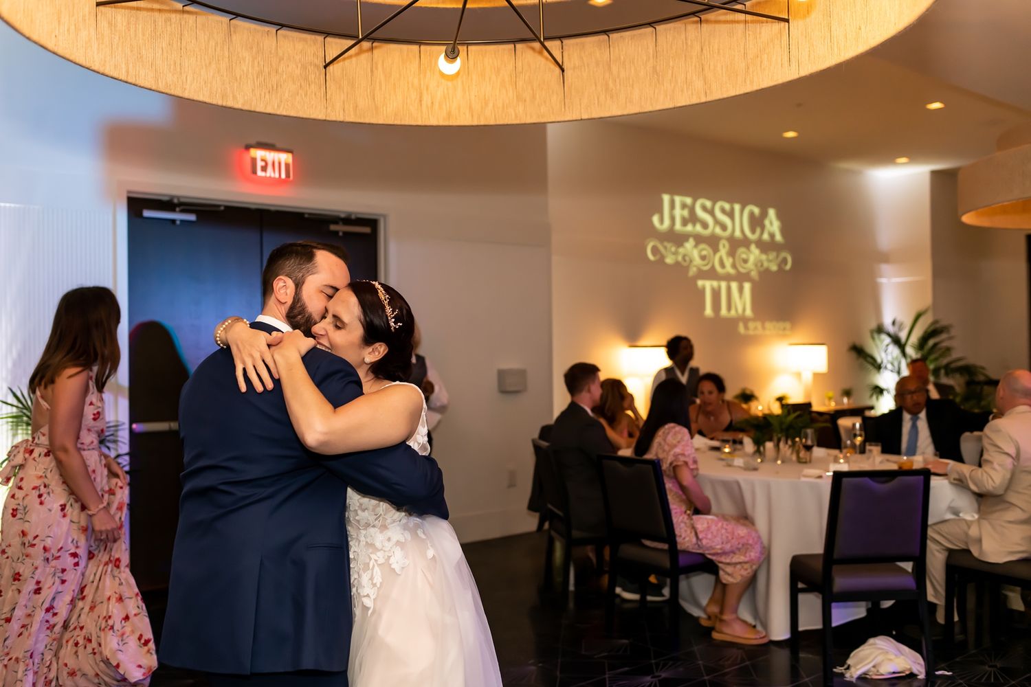 A romantic ballroom dance scene at a wedding reception with couples dancing under warm circular lighting.