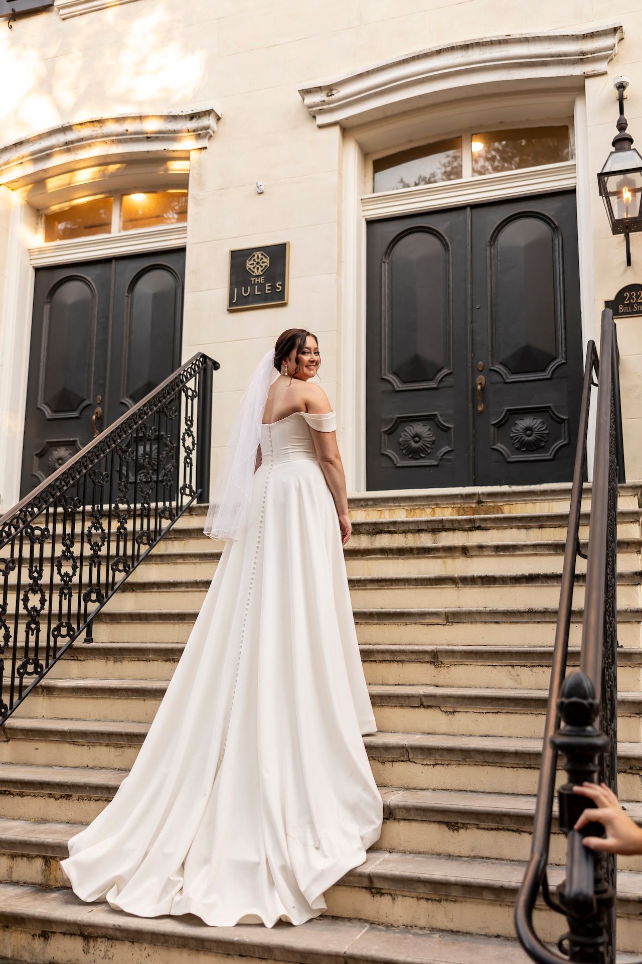 A sequence of wedding dress photos showing movement up stone steps with black railings and doors in an elegant setting.