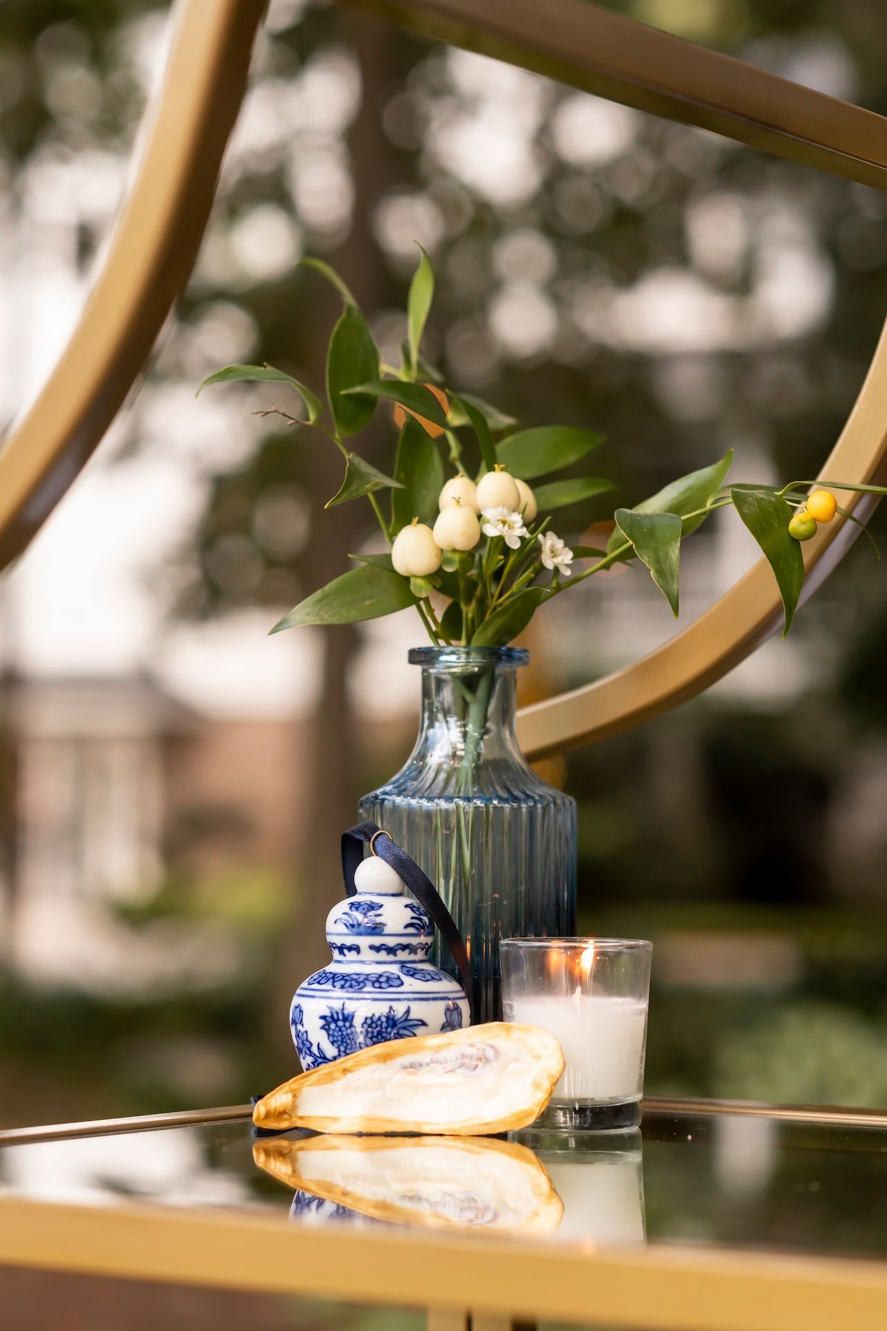 A delicate floral arrangement in a blue vase sits on a mirrored table with a glass of milk and sandwich.
