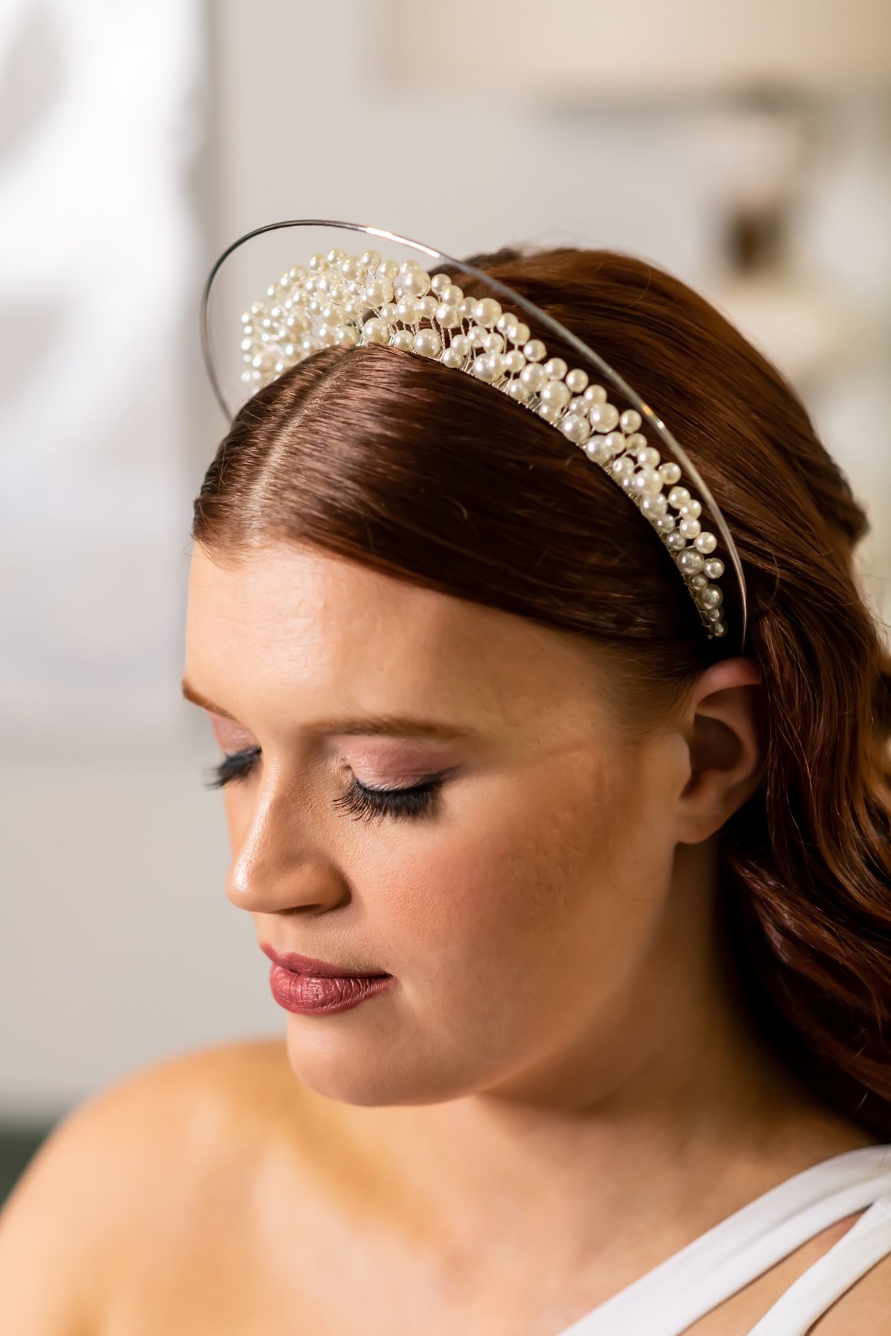 Close up details of pearl and crystal bridal headpiece with soft makeup and eye shadow at a wedding.