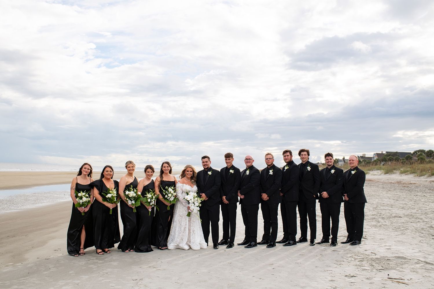 Wedding party takes portraits on the beach at Kasey and Lonnie's Shipyard Beach Club wedding.