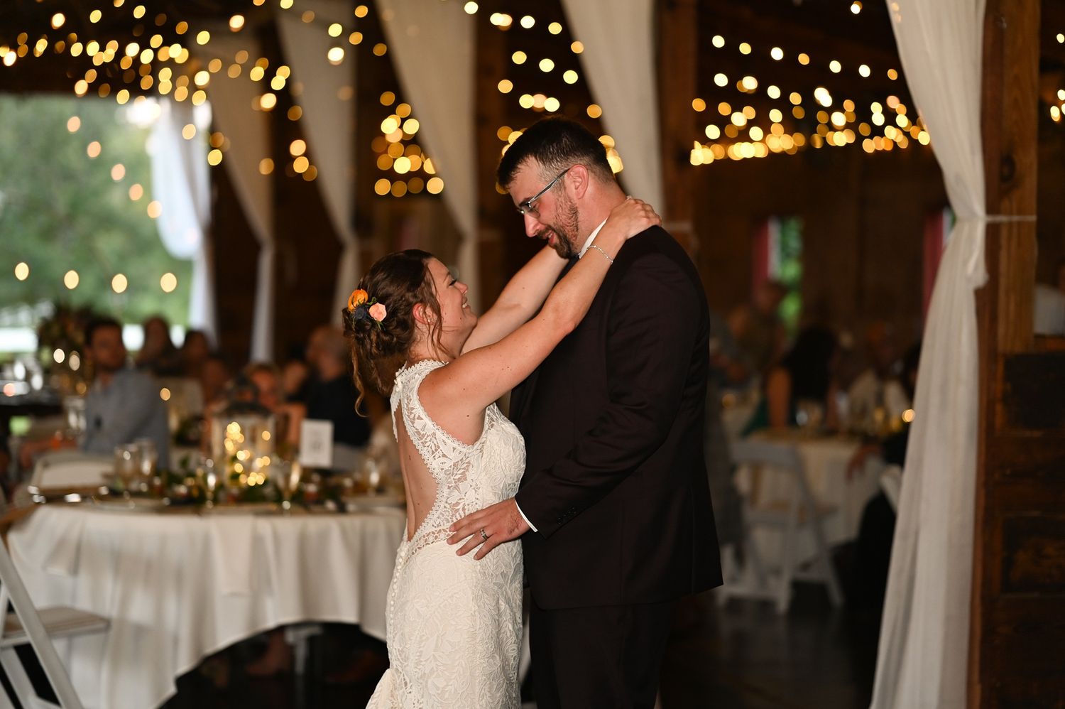 A romantic first dance at a wedding reception with twinkling lights creating a magical atmosphere in the background.