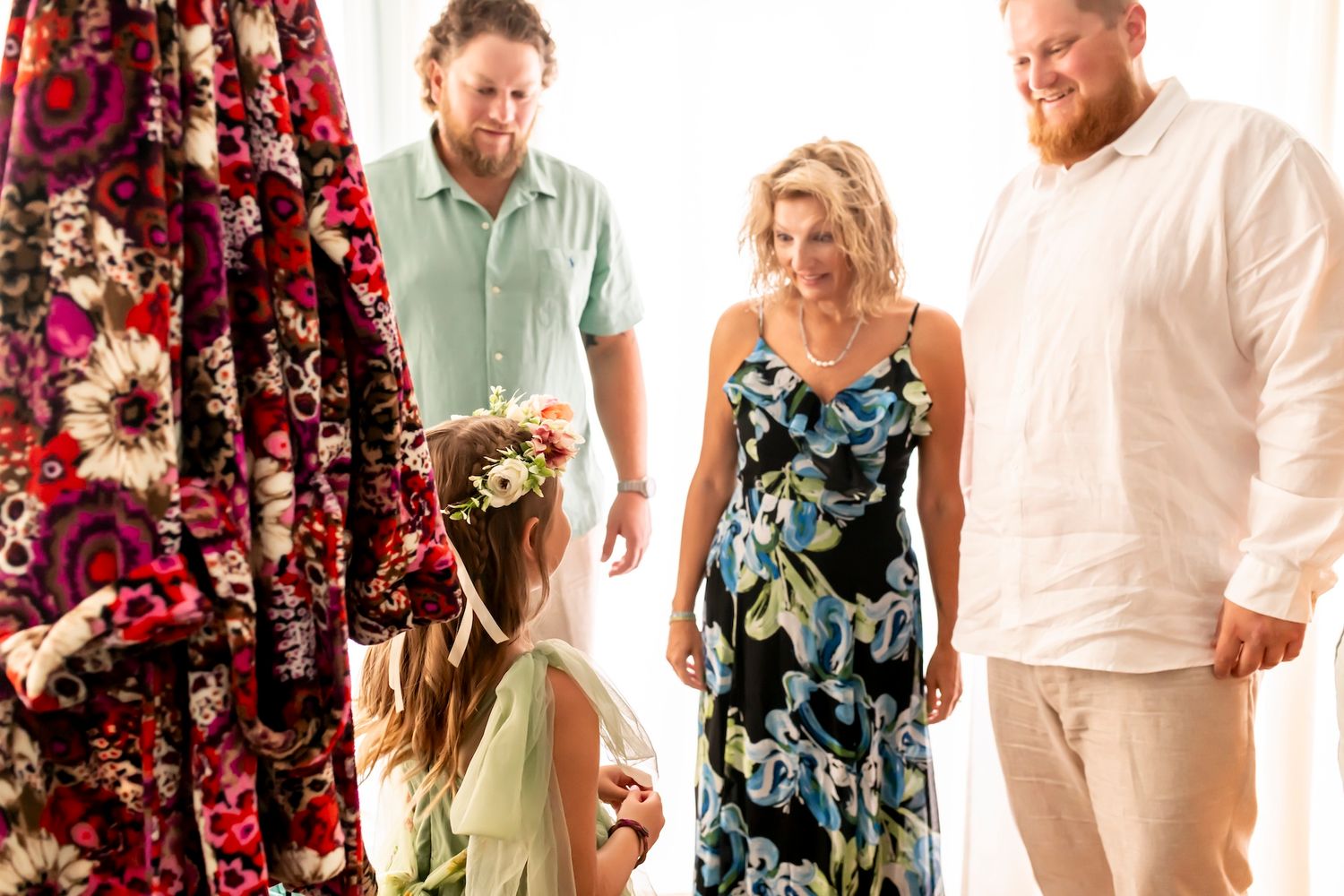 A small family gathering in front of floral curtains with people dressed in summer attire.