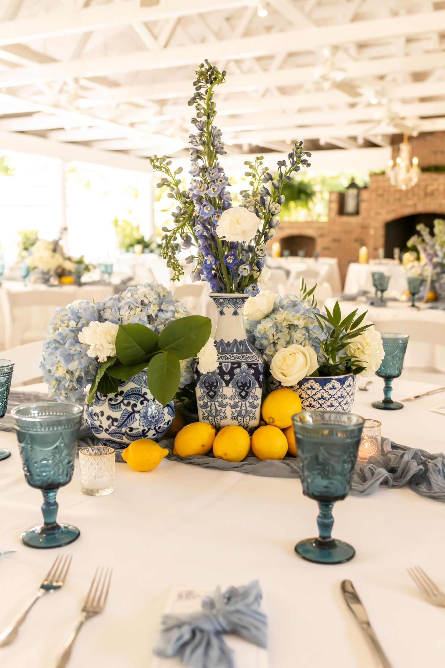 Blue and white table setting with citrus and floral centerpiece in blue and white chinoiserie vases.