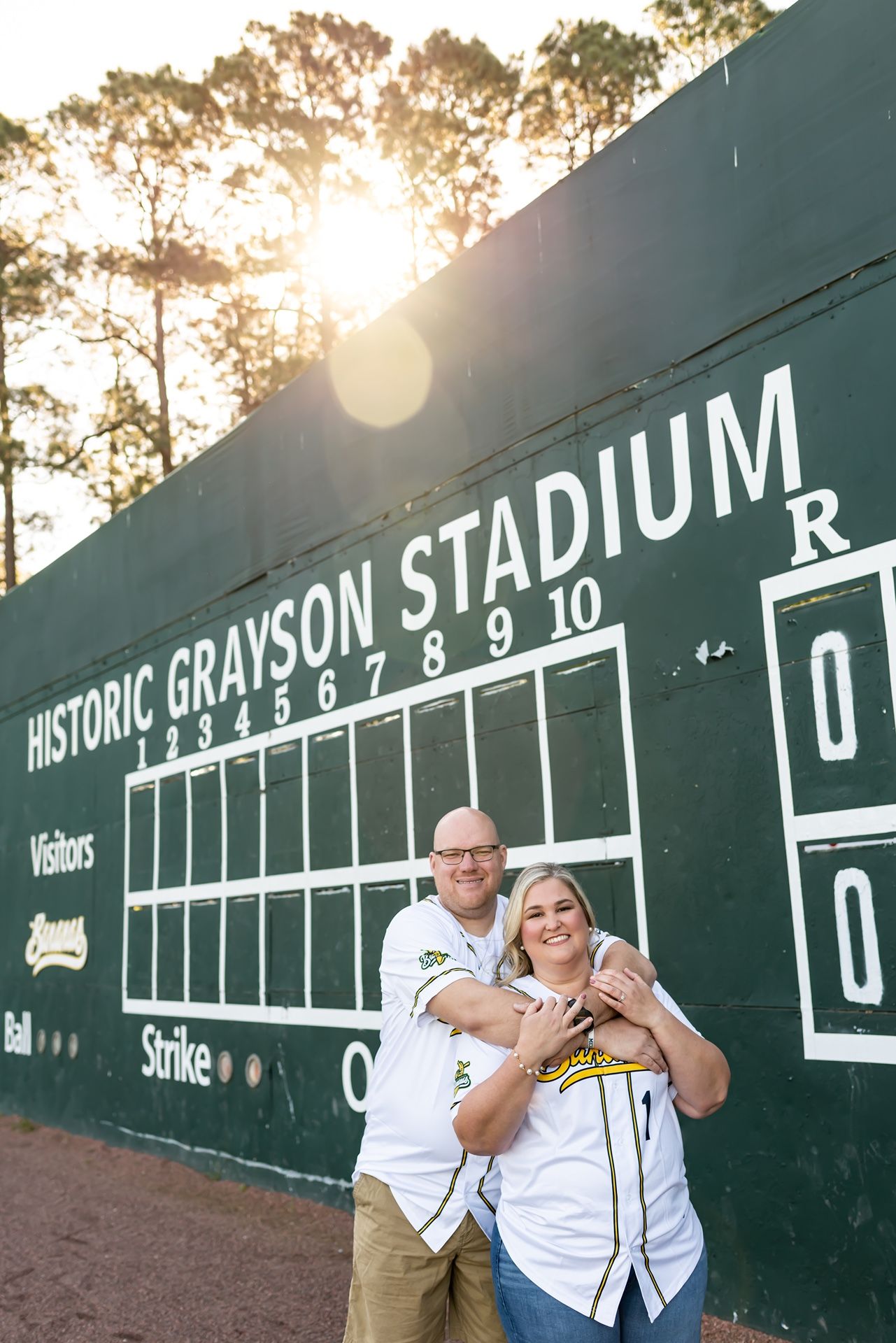 A large scoreboard at Historic Grayson Stadium is displayed with green paint and white lettering at golden hour.