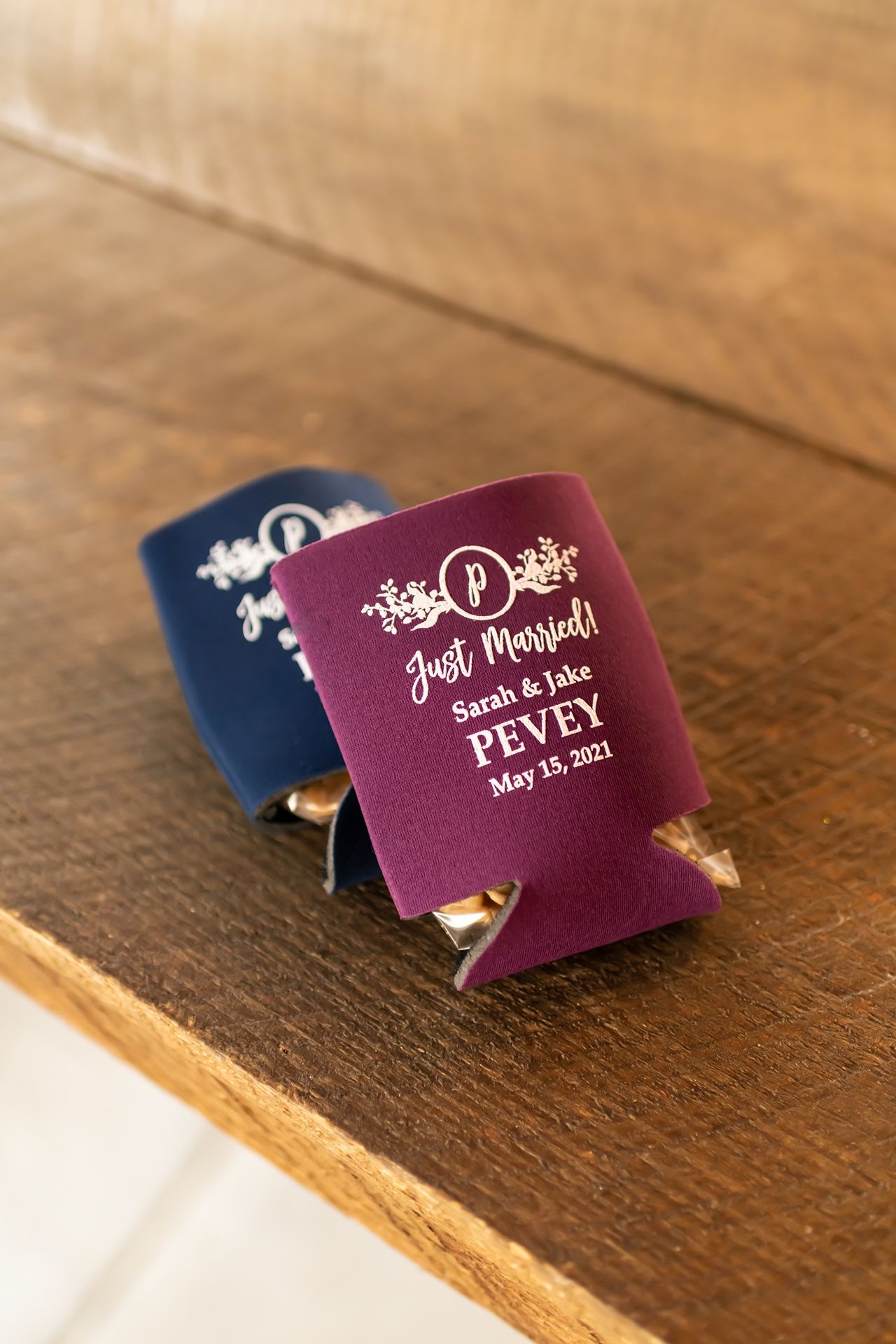 Burgundy wedding place cards with elegant white text and decorative flourishes sit on a rustic wooden surface.