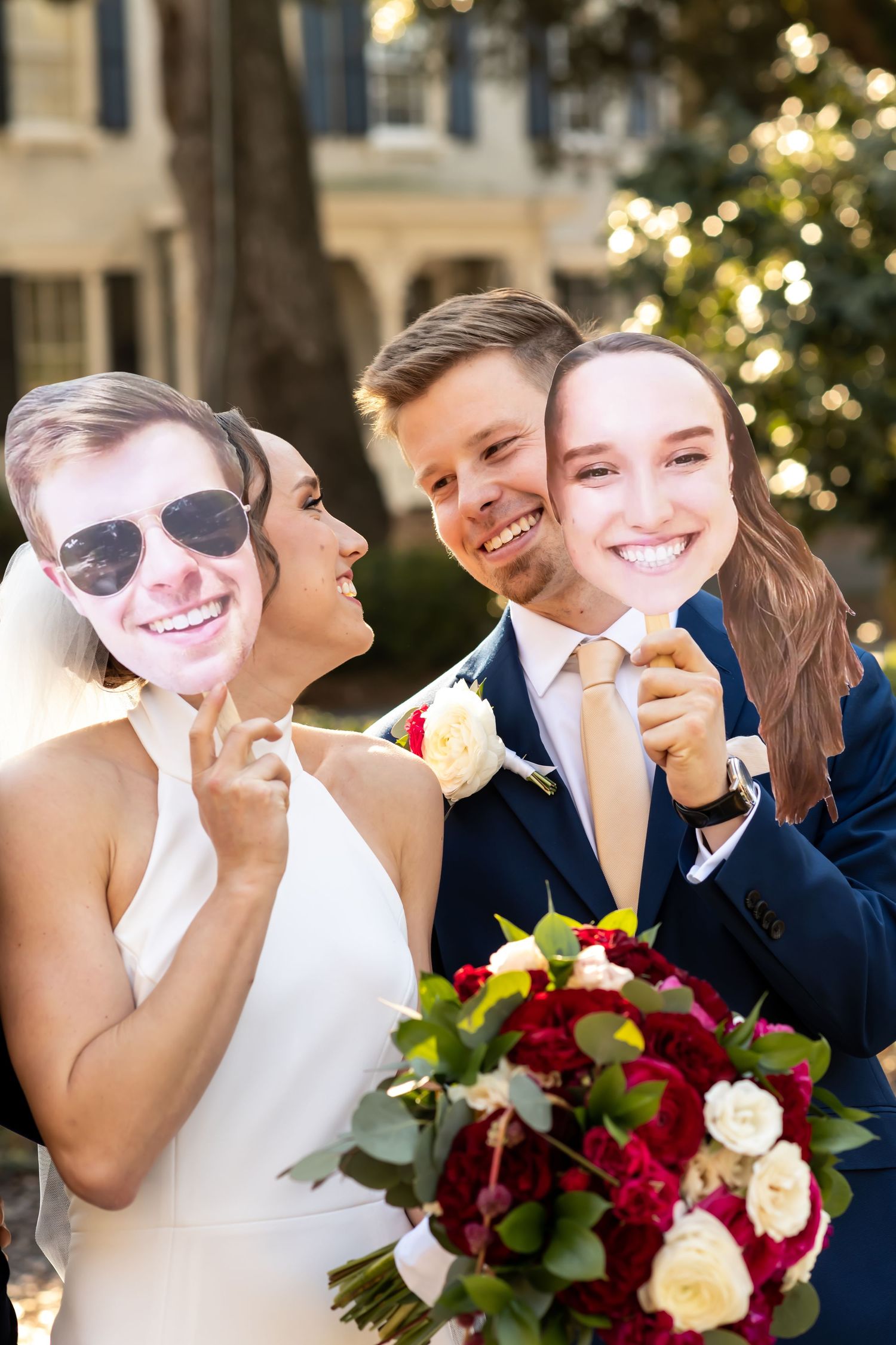 A joyful moment captured outdoors at a wedding celebration with a stunning red and white bouquet.