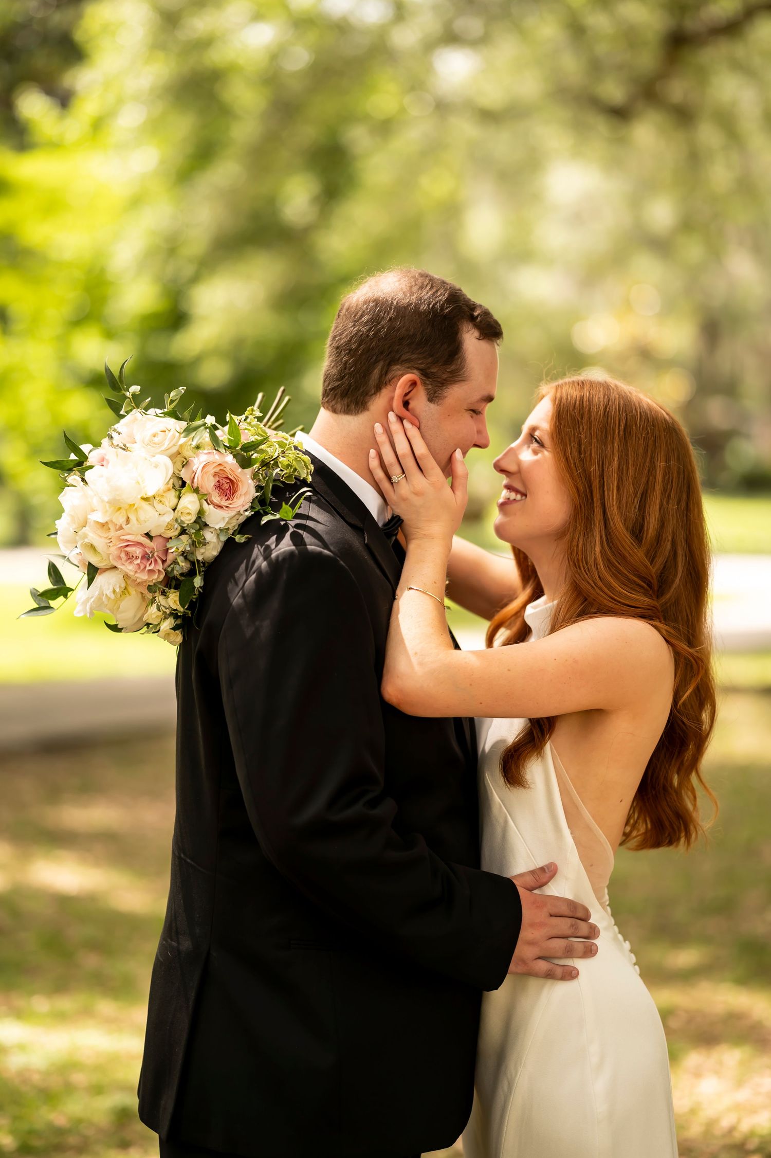 A romantic wedding moment captured outdoors with a beautiful bouquet of pink and white flowers in a natural setting.