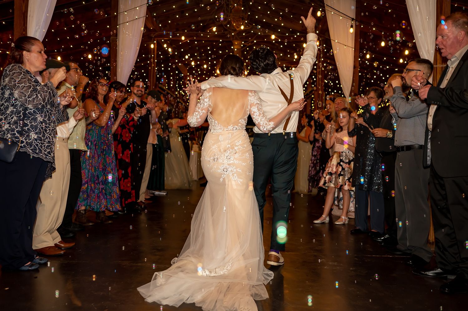 Newlyweds dance under sparklers held by guests during their romantic reception celebration at night.
