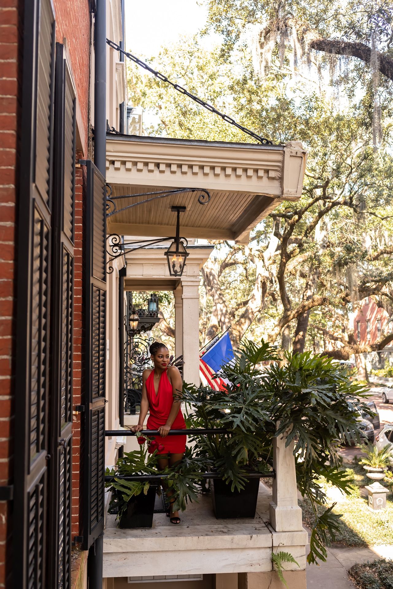 People enjoying a sunny day on a Southern-style porch with white columns and lush greenery at Beaufort's Historic District.