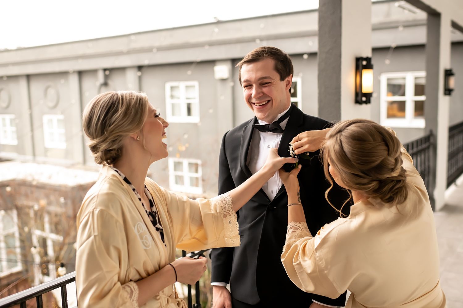 People laugh and enjoy themselves while socializing on a balcony during an elegant formal event.