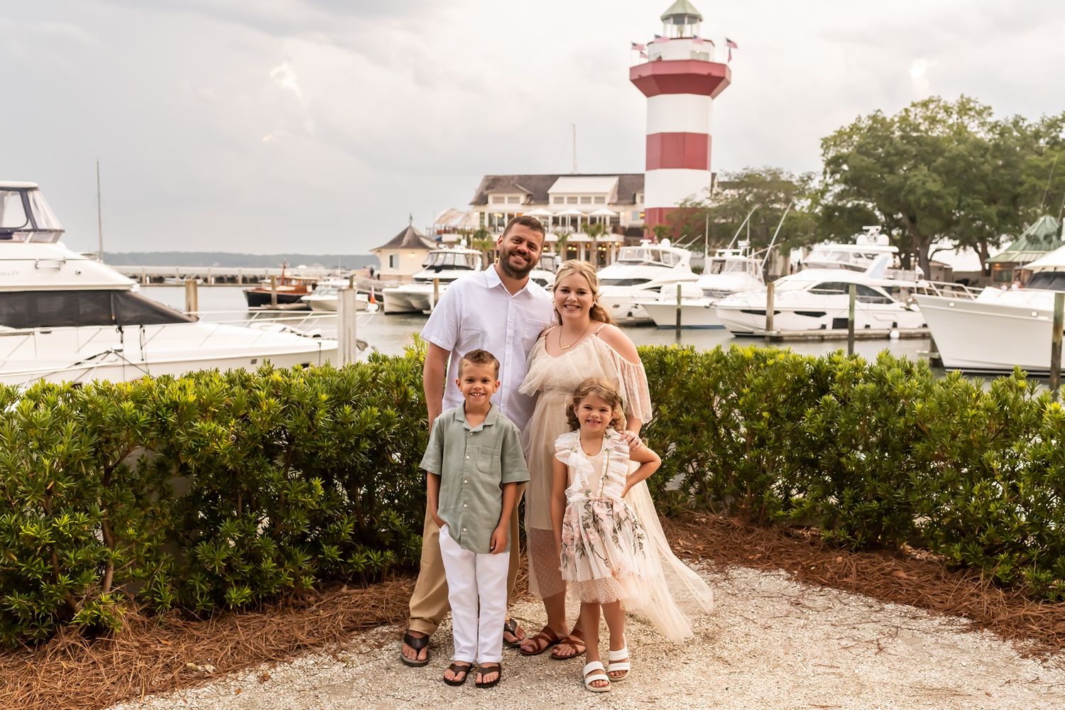 A waterfront lighthouse ceremony setup with white chairs and coastal decor on the grounds of a harbor.