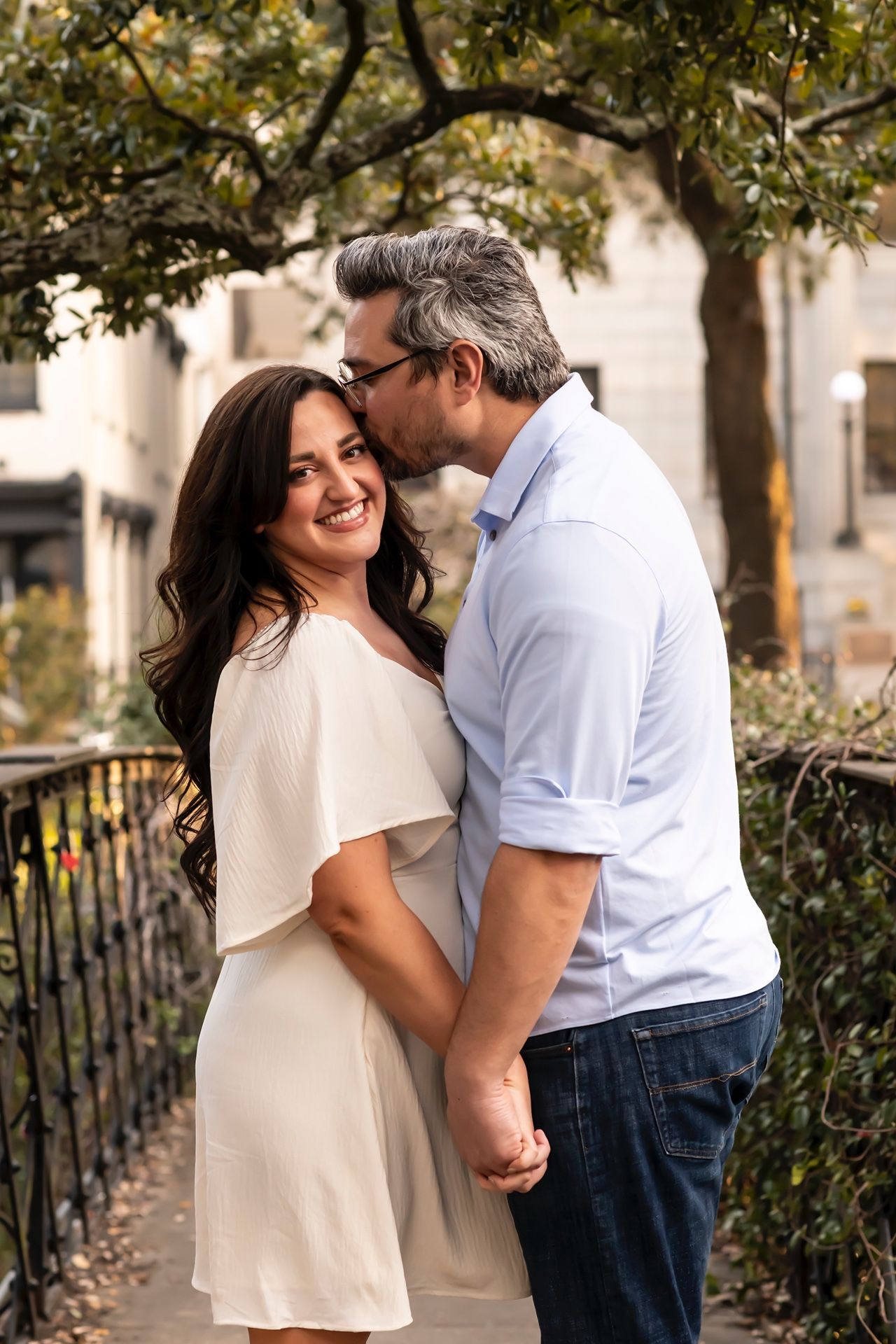 A couple shares romantic moments in a series of outdoor portraits against trees and greenery.
