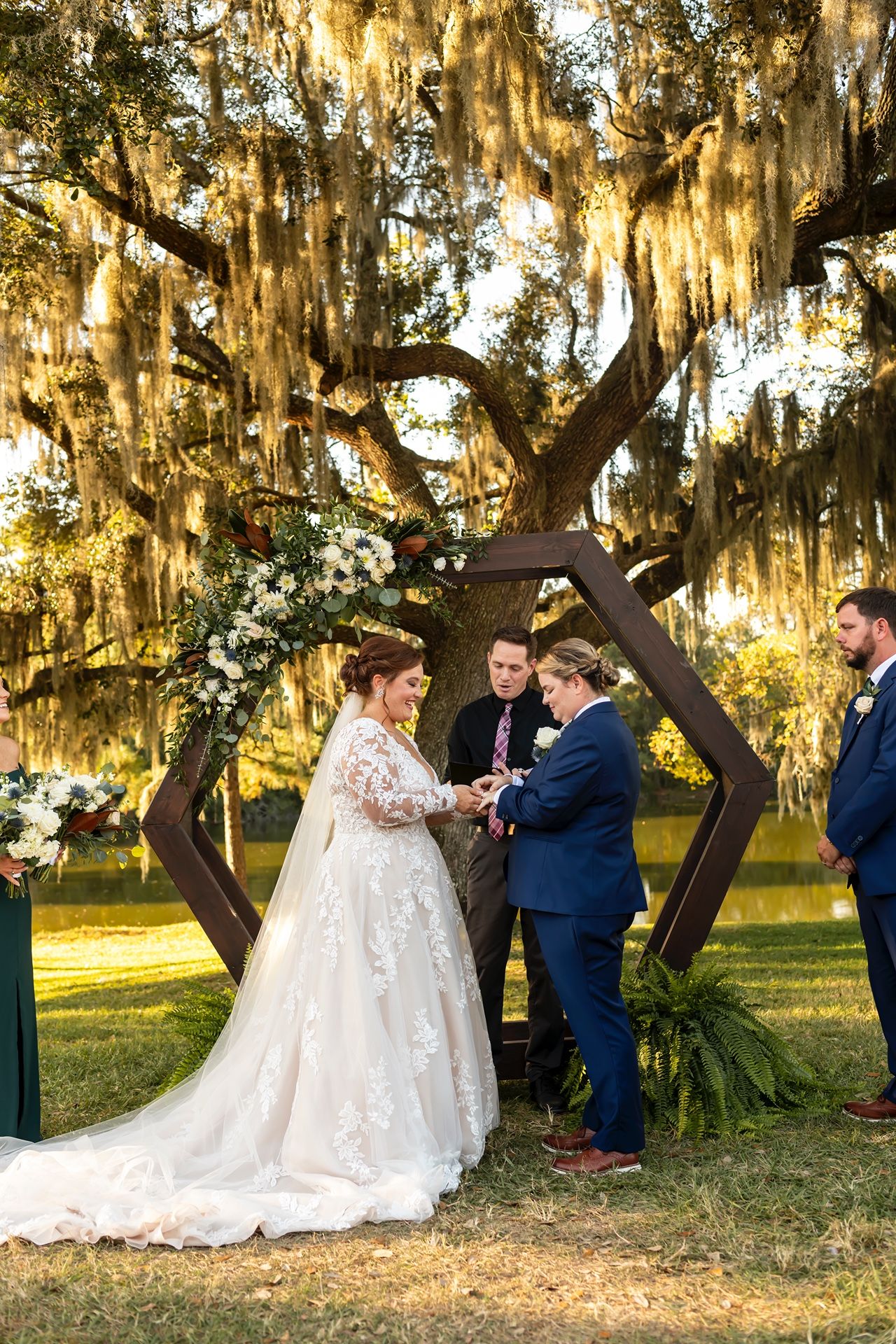 Couple shares romantic sunset moments under Spanish moss-draped oak trees during outdoor wedding photo session.
