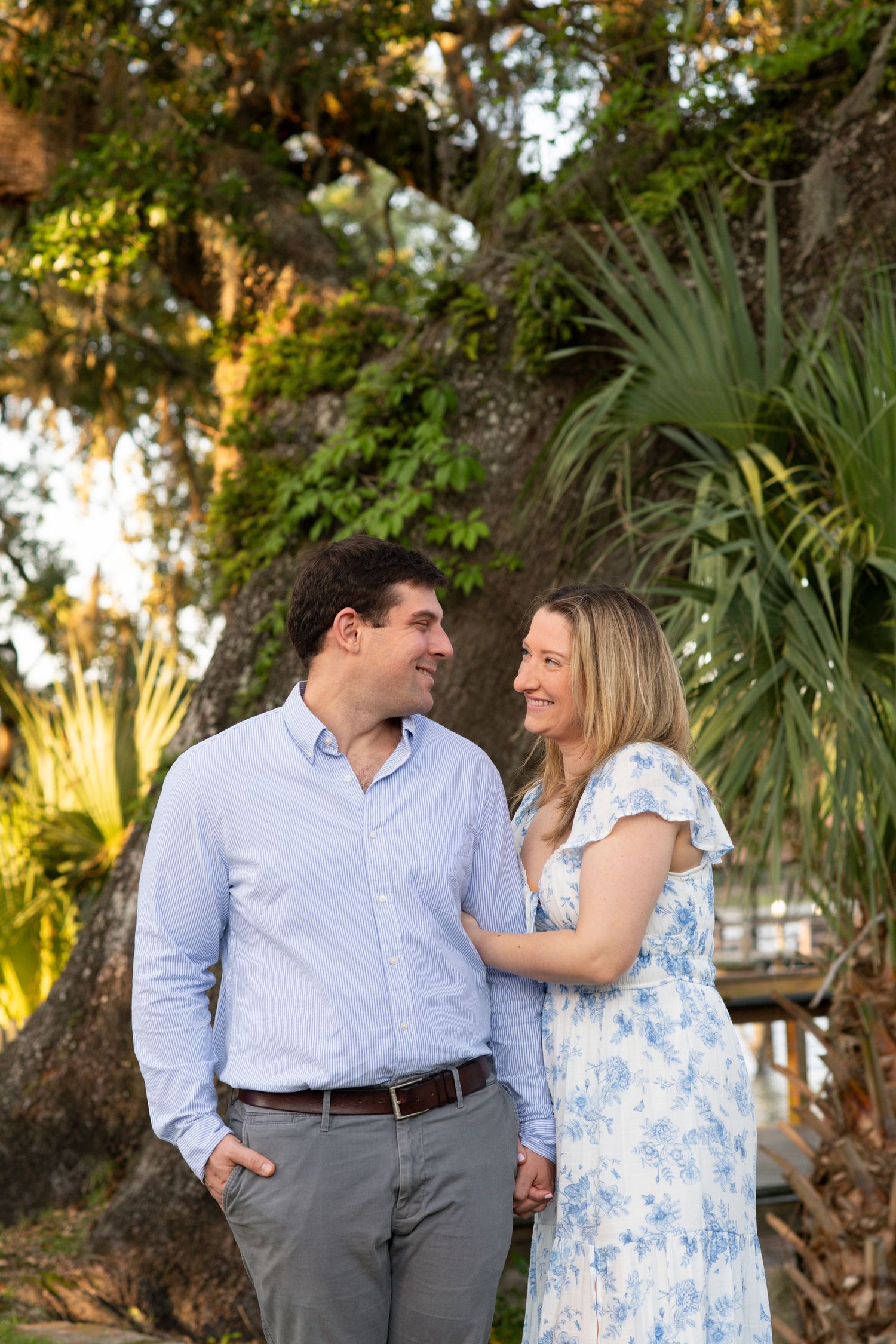 A couple shares a romantic moment together in a lush tropical garden setting with palm trees and golden sunlight.