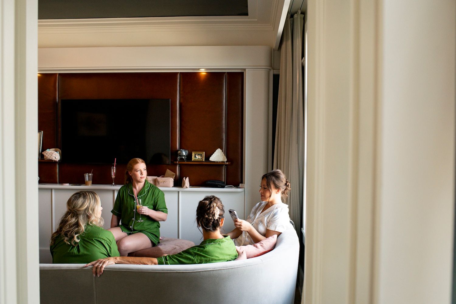 Group of friends wearing matching green shirts relax together on a white bed.