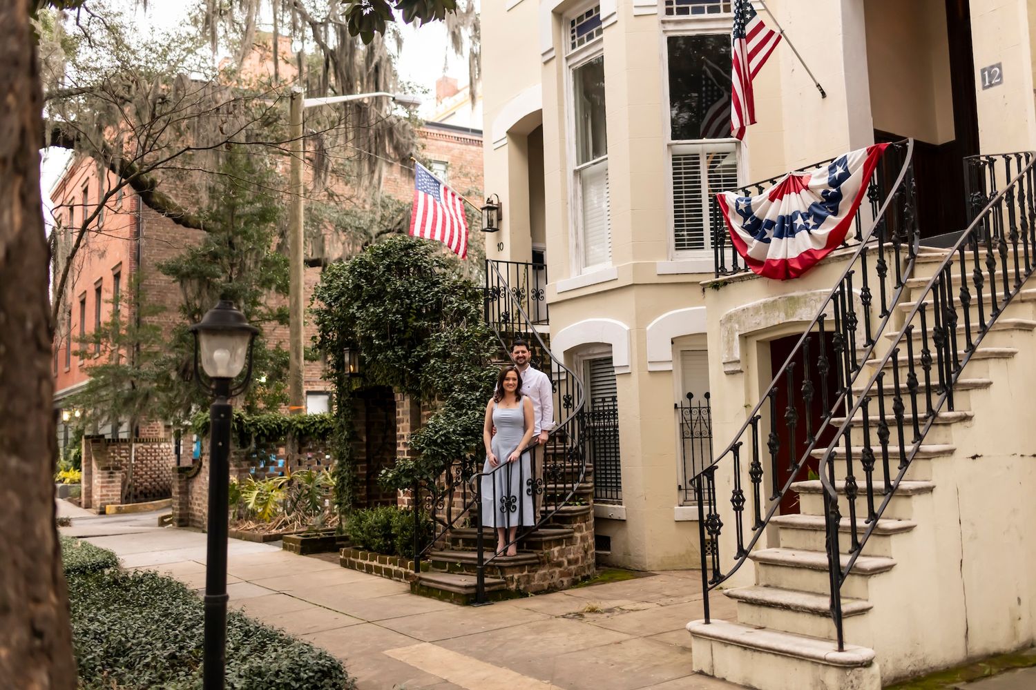 Historic residential street in Savannah Georgia with American flags and patriotic bunting decorating brownstone buildings.