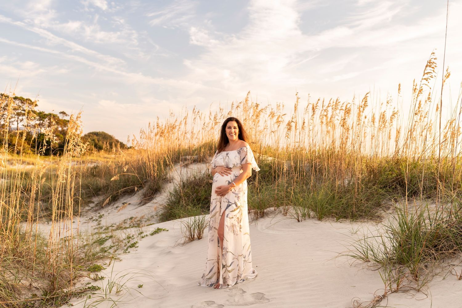Couple walking along scenic beach pathway through sea oats at sunset creating romantic coastal ambiance.