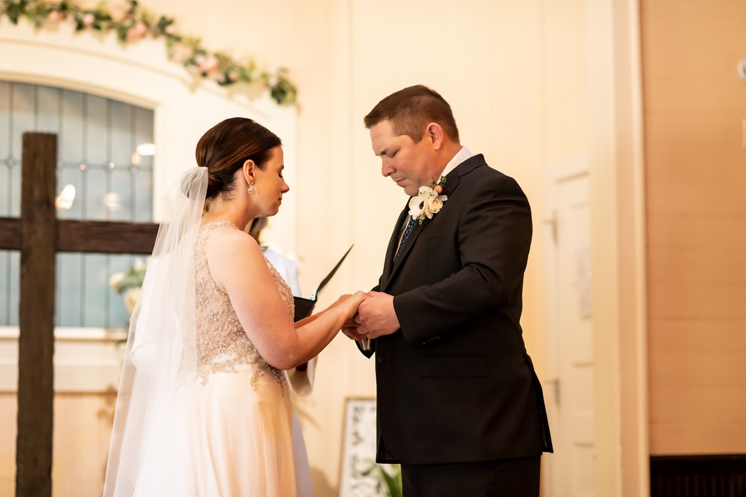 A couple inside a church exchanging rings during their wedding ceremony with elegant floral decor.