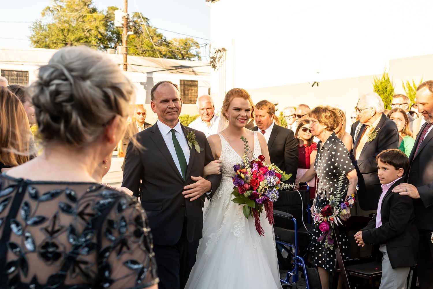 Wedding guests gather outdoors at golden hour reception, enjoying conversations and celebrating under natural light.