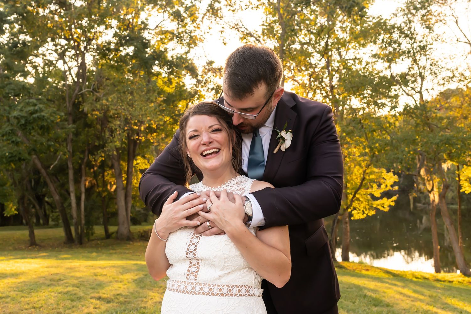 Joyful couple share an intimate moment at sunset in a lush park setting near a tranquil lake.