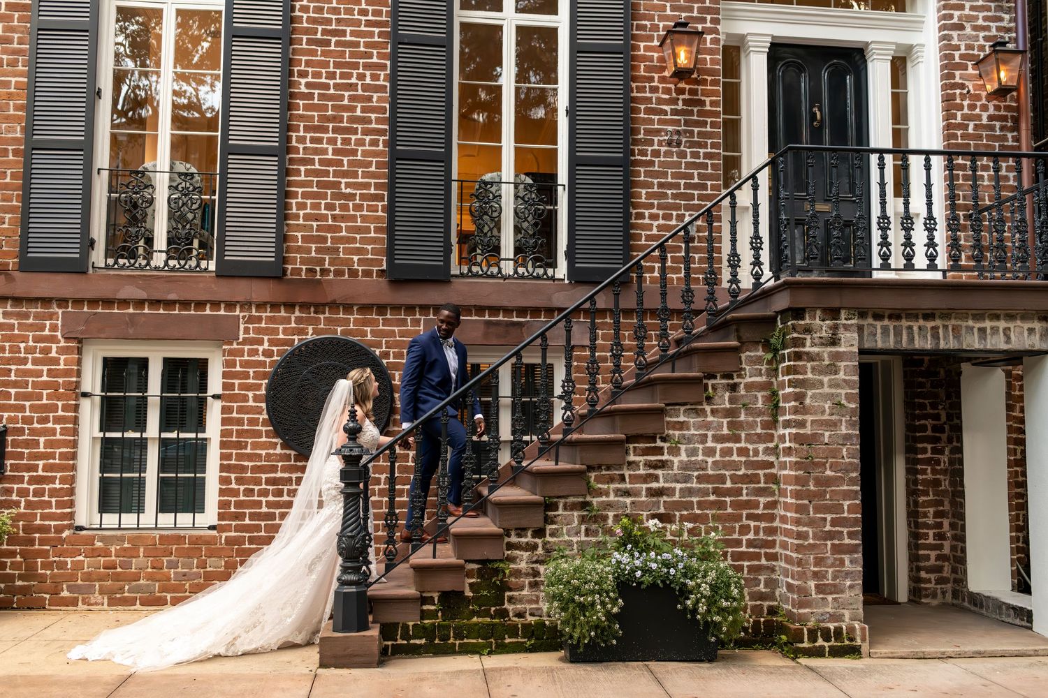 Brick townhouse facade with white trim and ornate iron railings along steps in an urban neighborhood setting.