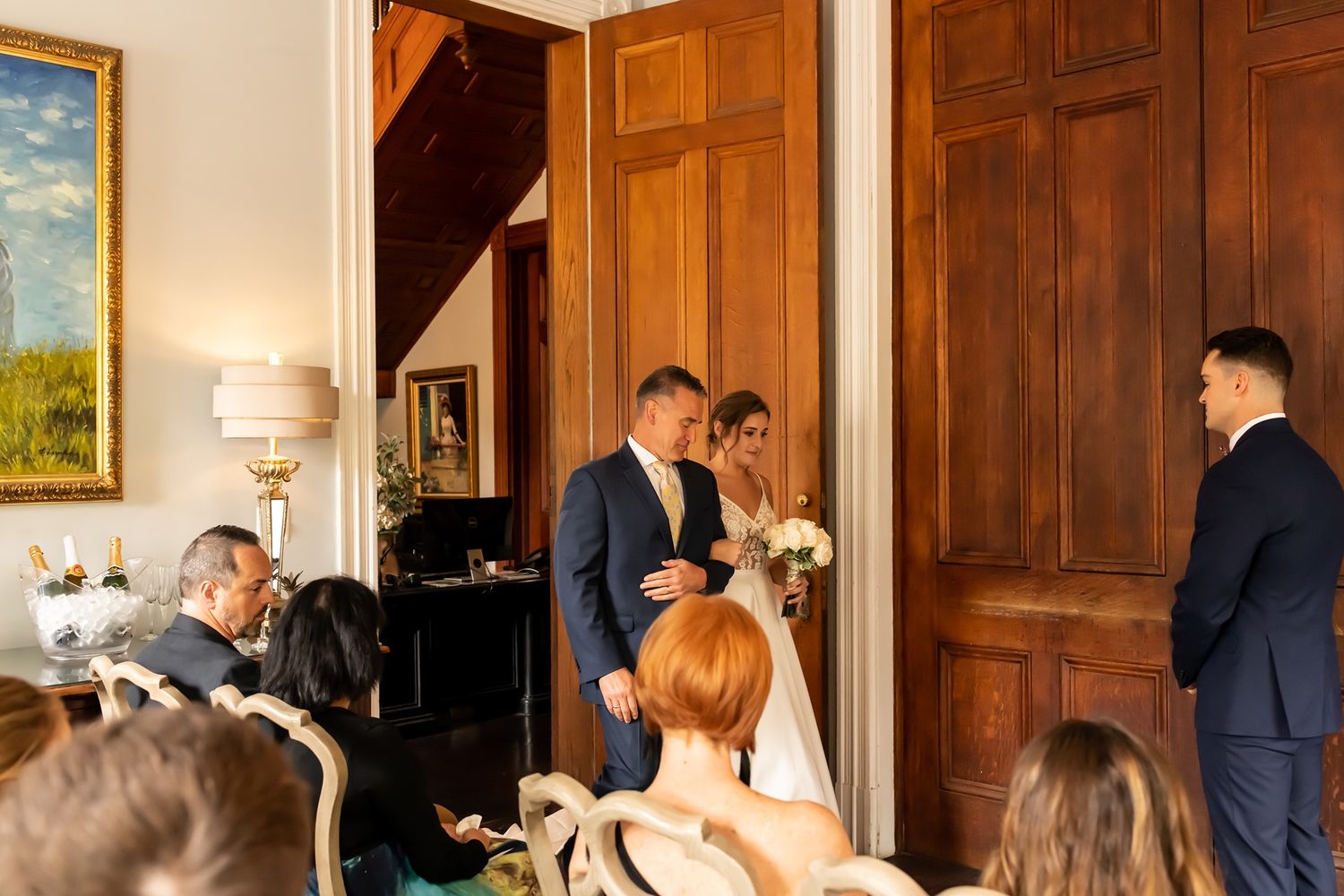 A wood-paneled room interior featuring couples gathered around for an indoor ceremony.