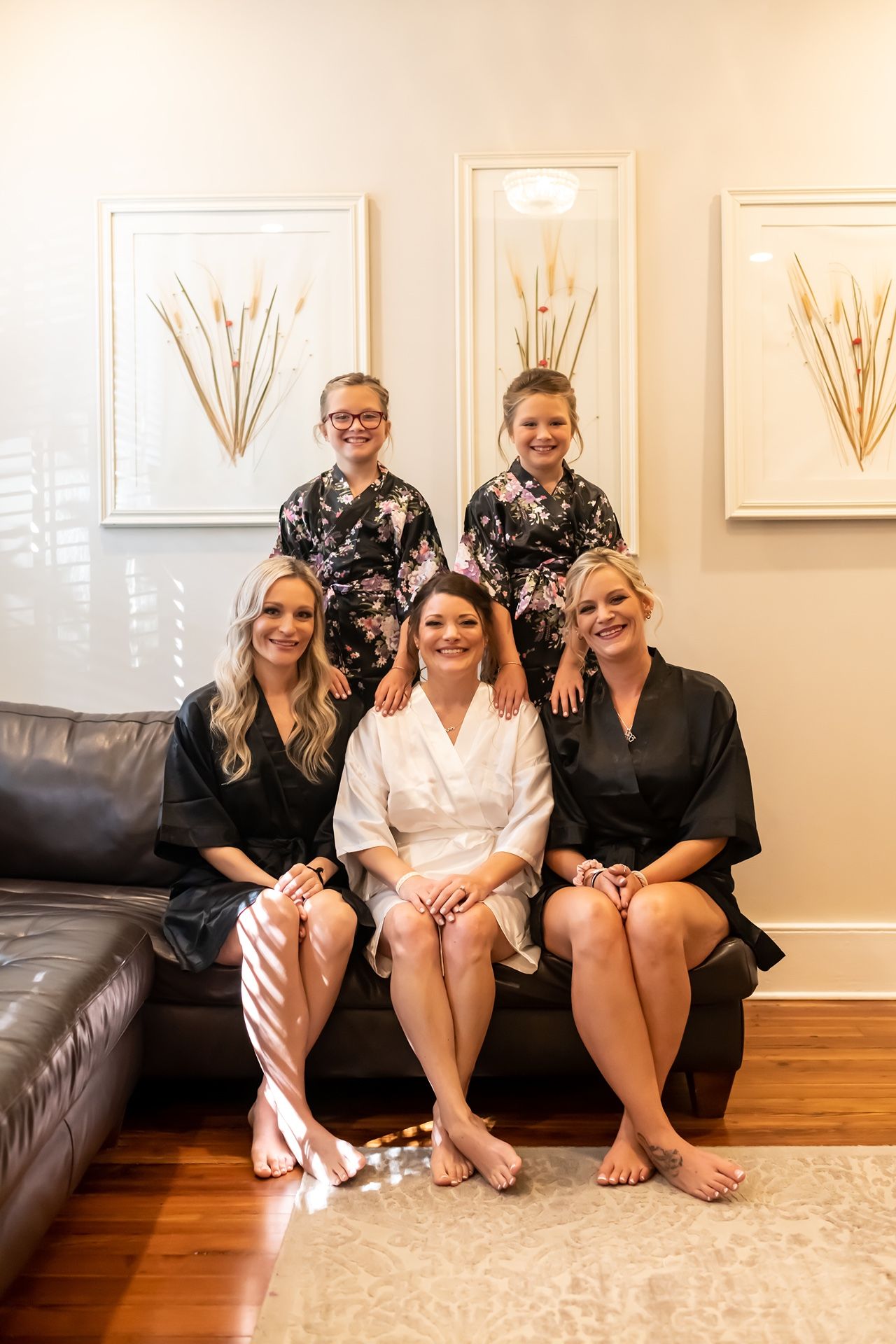 Group of people in black and white robes sitting on a couch smiling during a wedding preparation photoshoot.