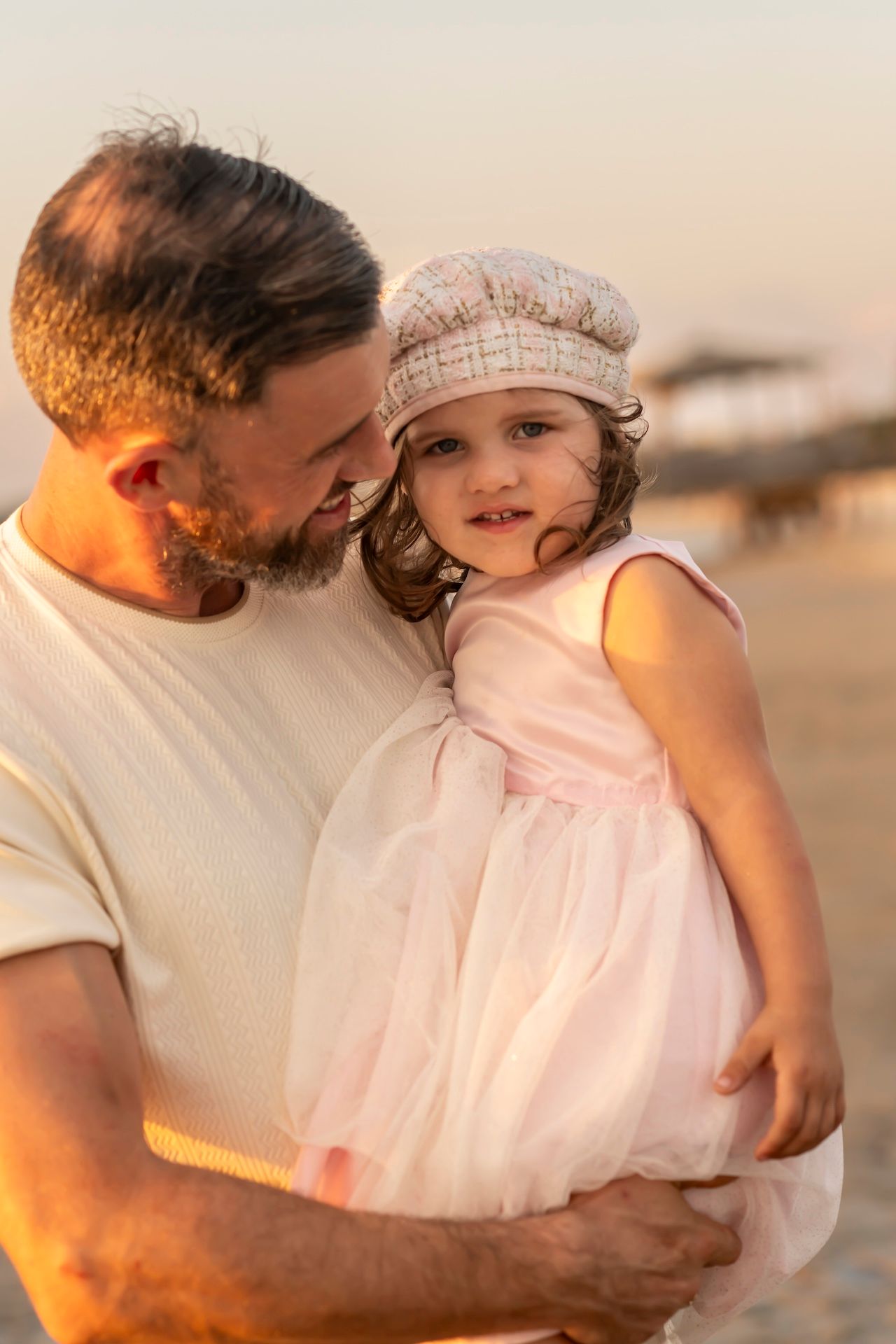 A tender sequence of warm sunset moments shared on a sandy beach in soft lighting.