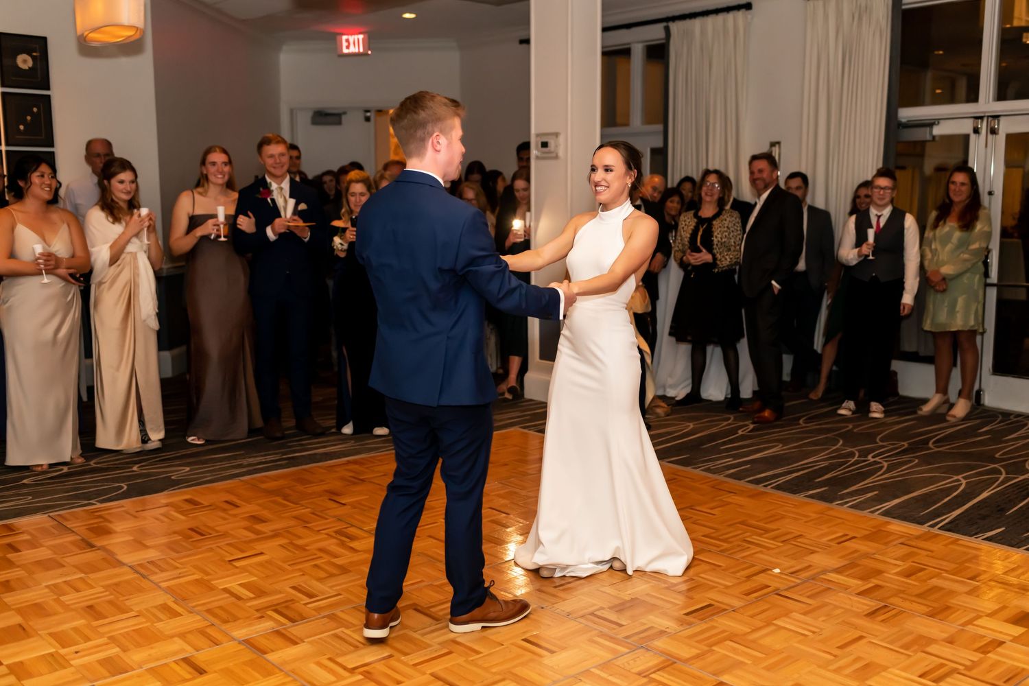 Wedding guests gather around the dance floor watching couples dance during an evening reception celebration.