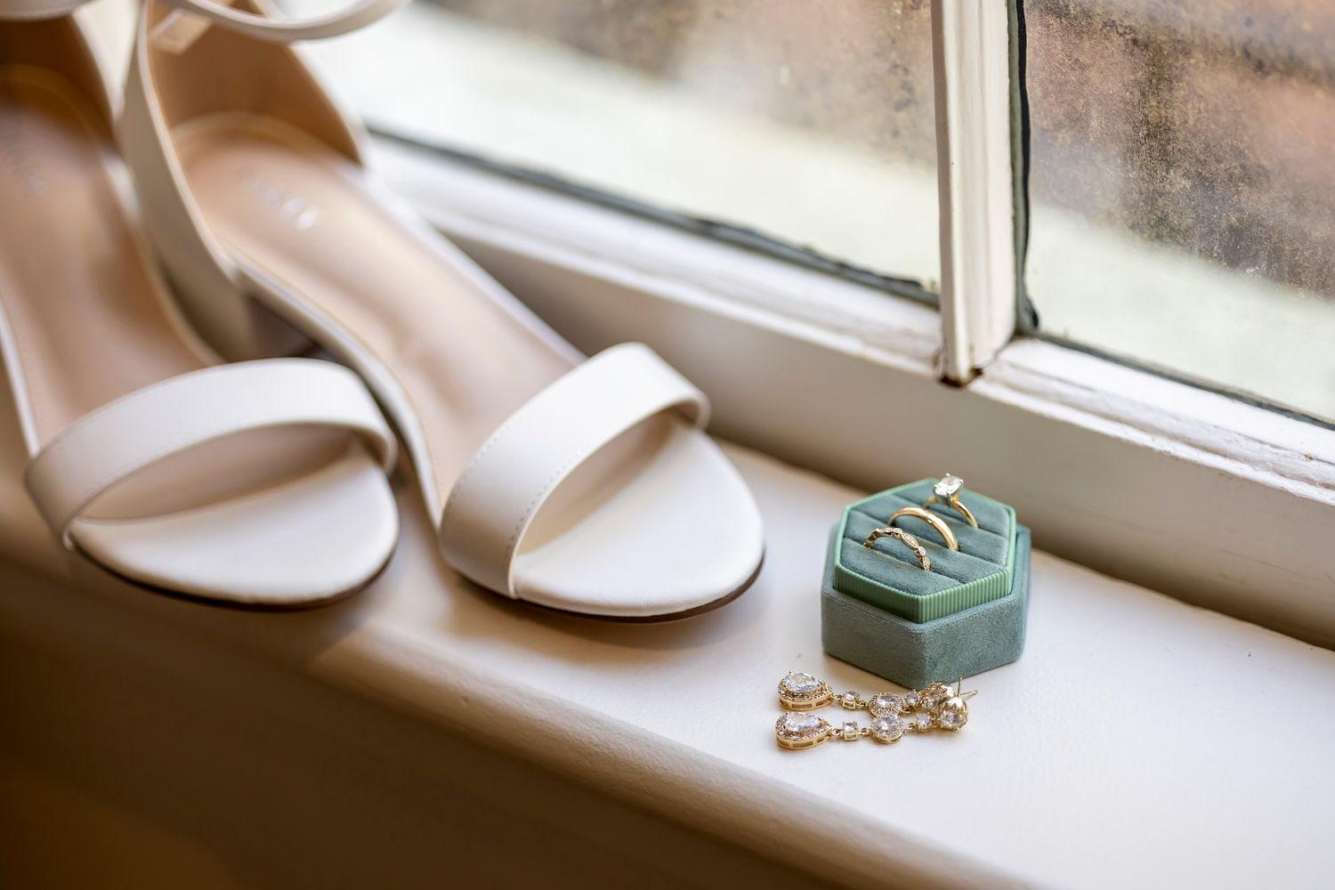 White bridal sandals and turquoise ring box sit elegantly on a sunny windowsill.