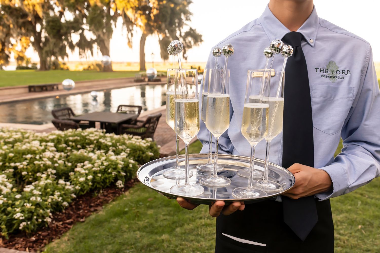 Professional catering staff serving champagne and appetizers at an elegant outdoor garden event.